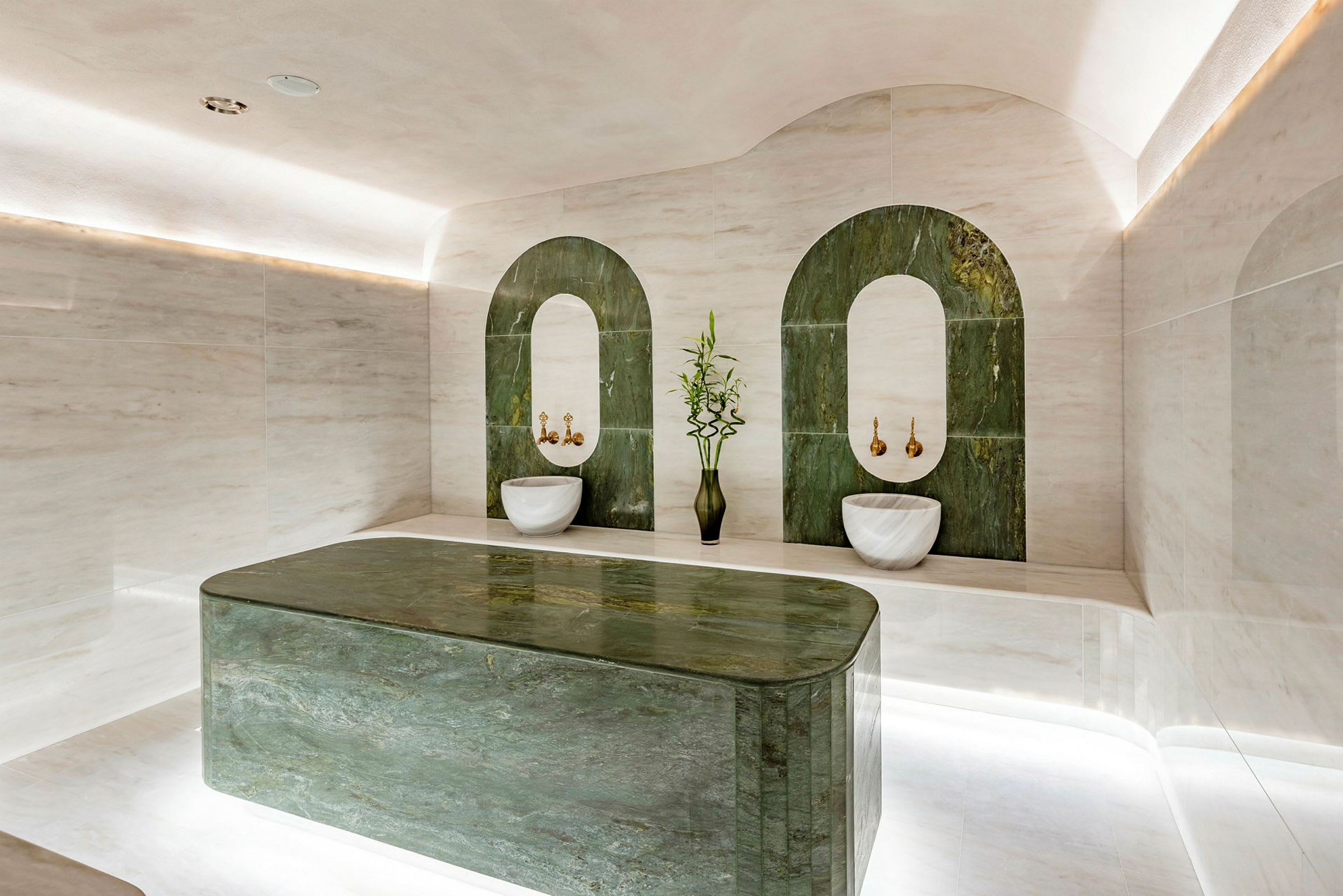 Interiör av ett lyxigt hamam med gröna detaljer och rundade vita tvättstenar. (AI-genererad text)