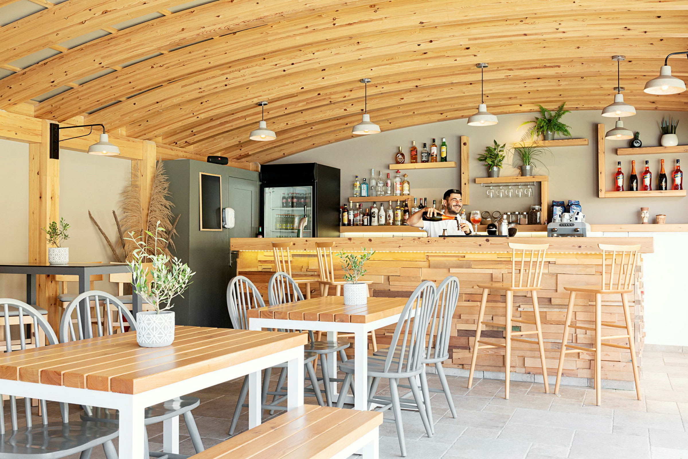 En kaféteria med träinredning, bord, stolar och en bardisk. (AI-genererad text)