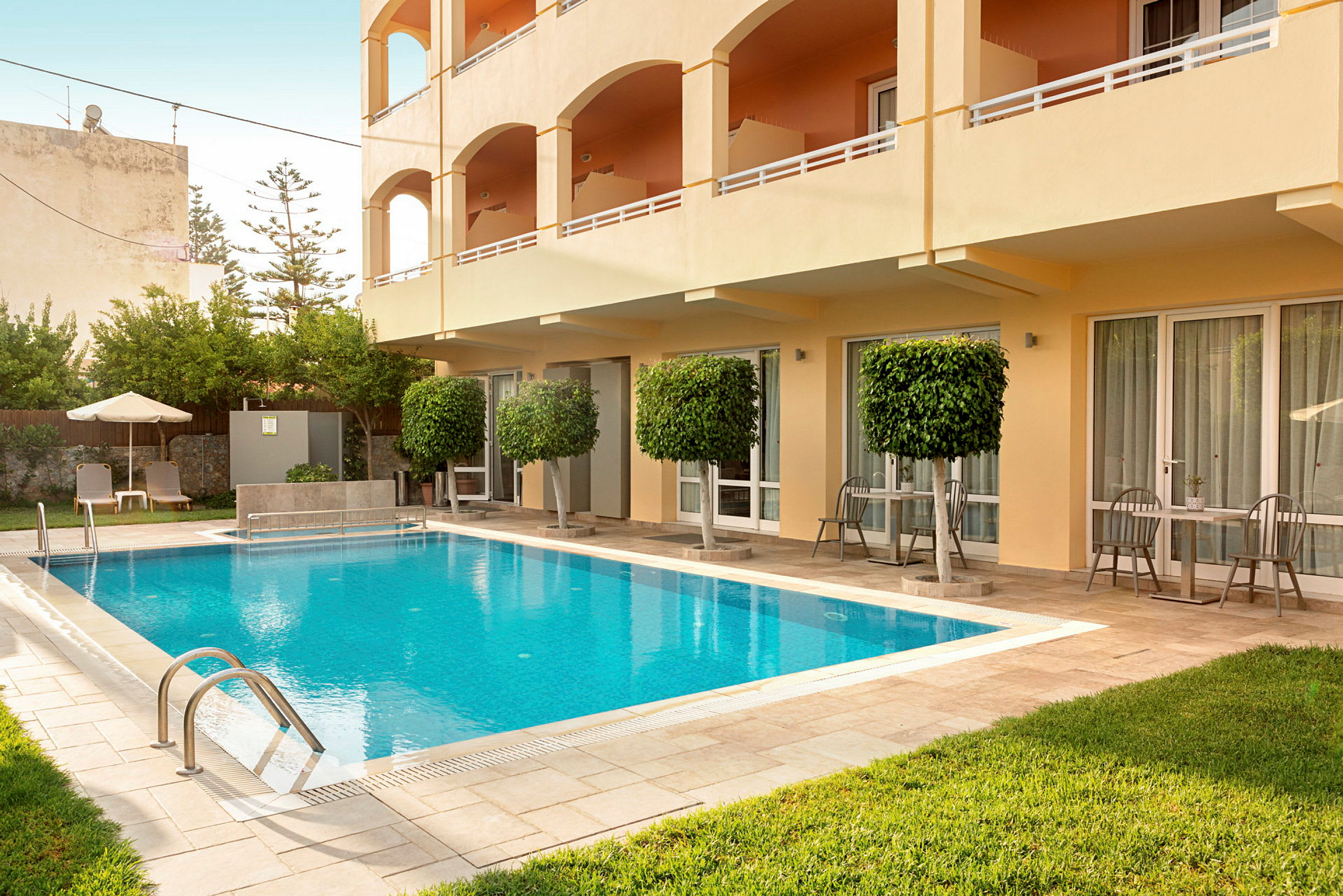 En utomhuspool vid ett hotell med solstolar och möblerade uteplatser. (AI-genererad text)