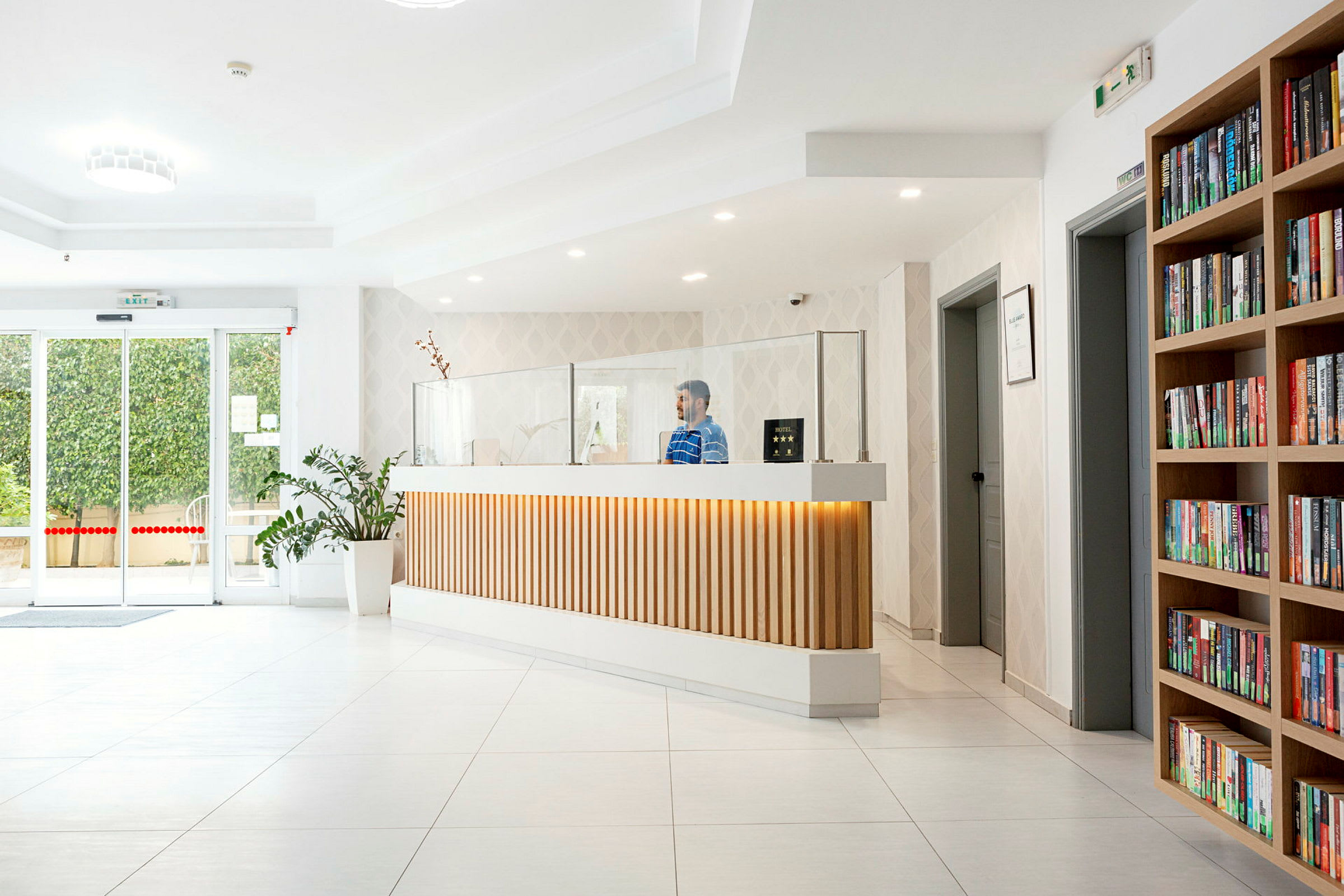 Modern hotellreception med bokhylla och växt. (AI-genererad text)