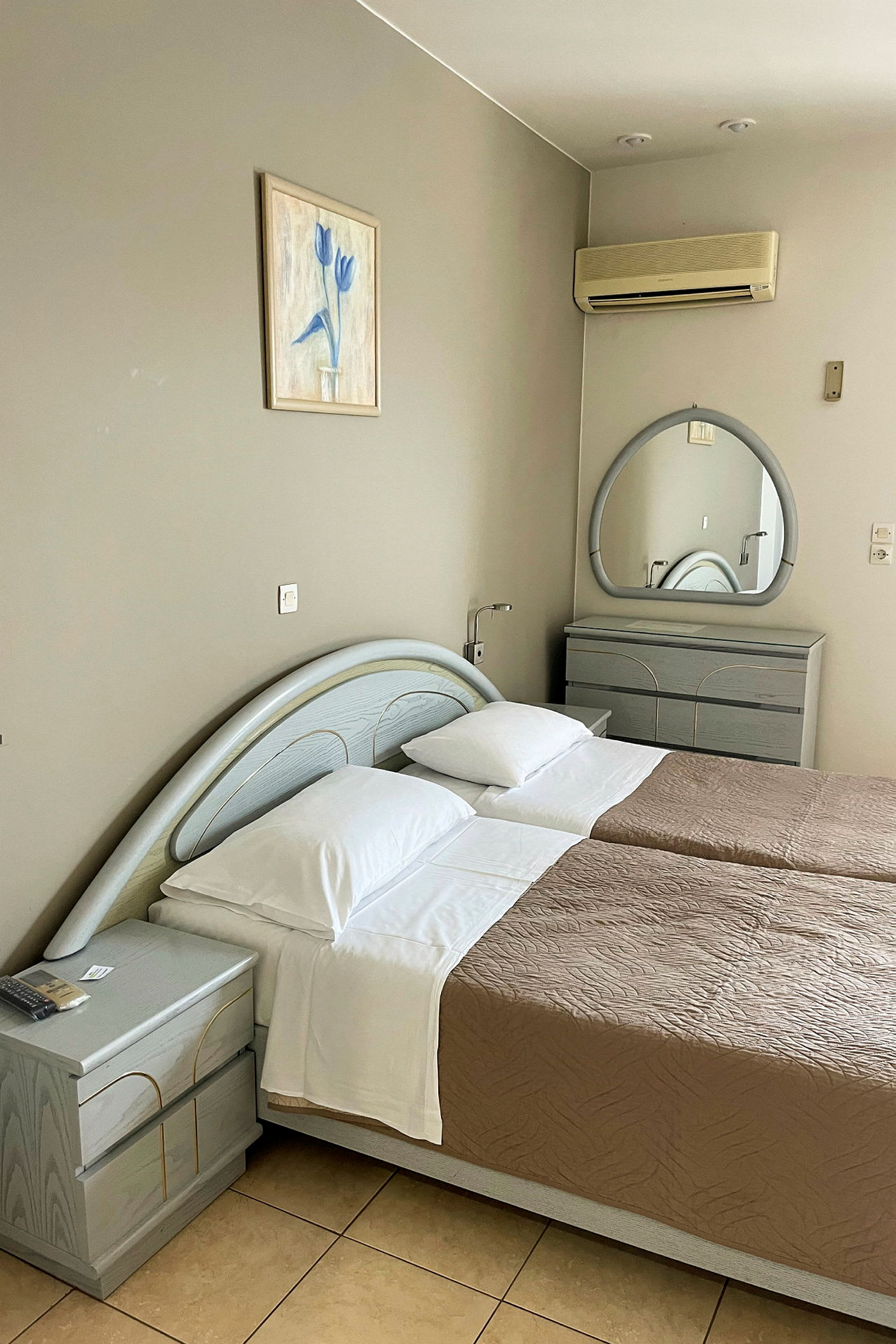 Ett hotellrum med två enkelsängar, en byrå och en vägg spegel. (AI-genererad text)