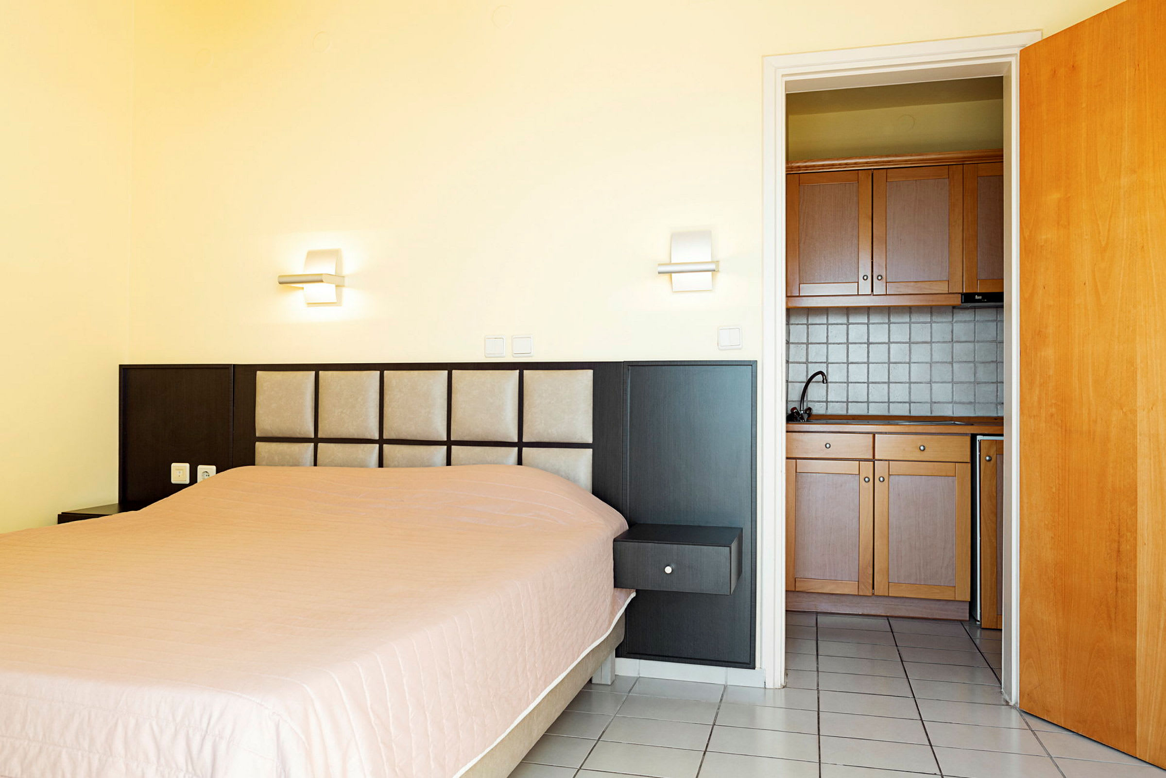 Hotellrum med säng och mini-kök. (AI-genererad text)