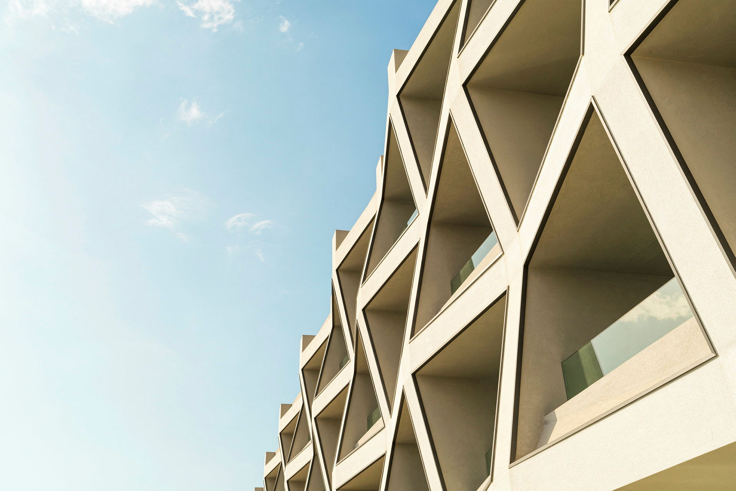 Exteriör av en byggnad med geometriska fönsterformer, mot en klar himmel. (AI-genererad text)