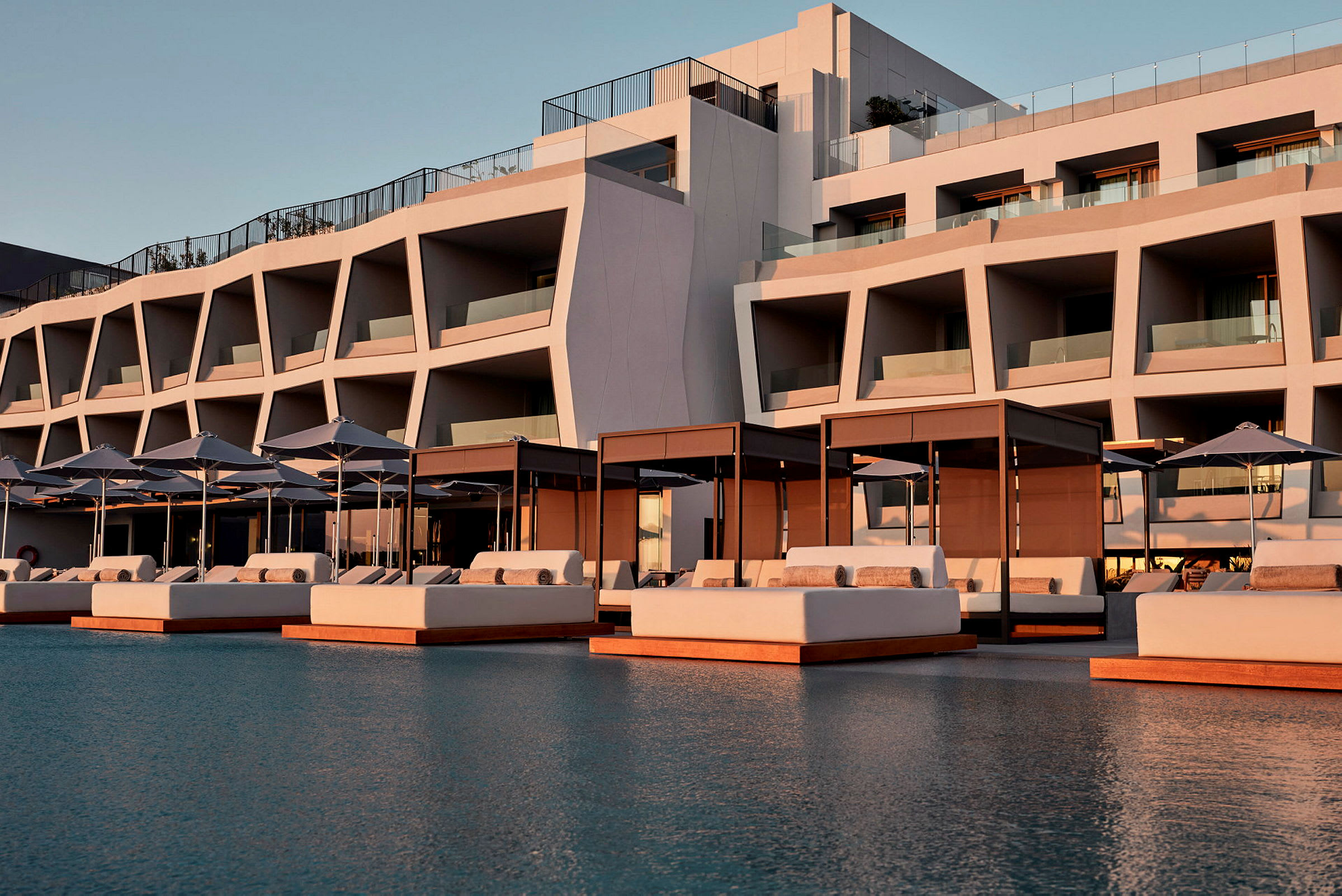 Modern hotellbyggnad med solbäddar och parasoller vid en pool. (AI-genererad text)