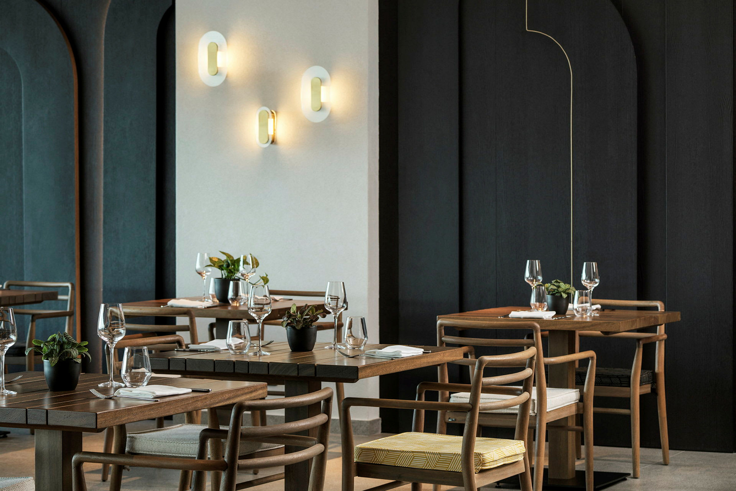 En elegant restaurang med träbord, stolar och väggbelysning. (AI-genererad text)