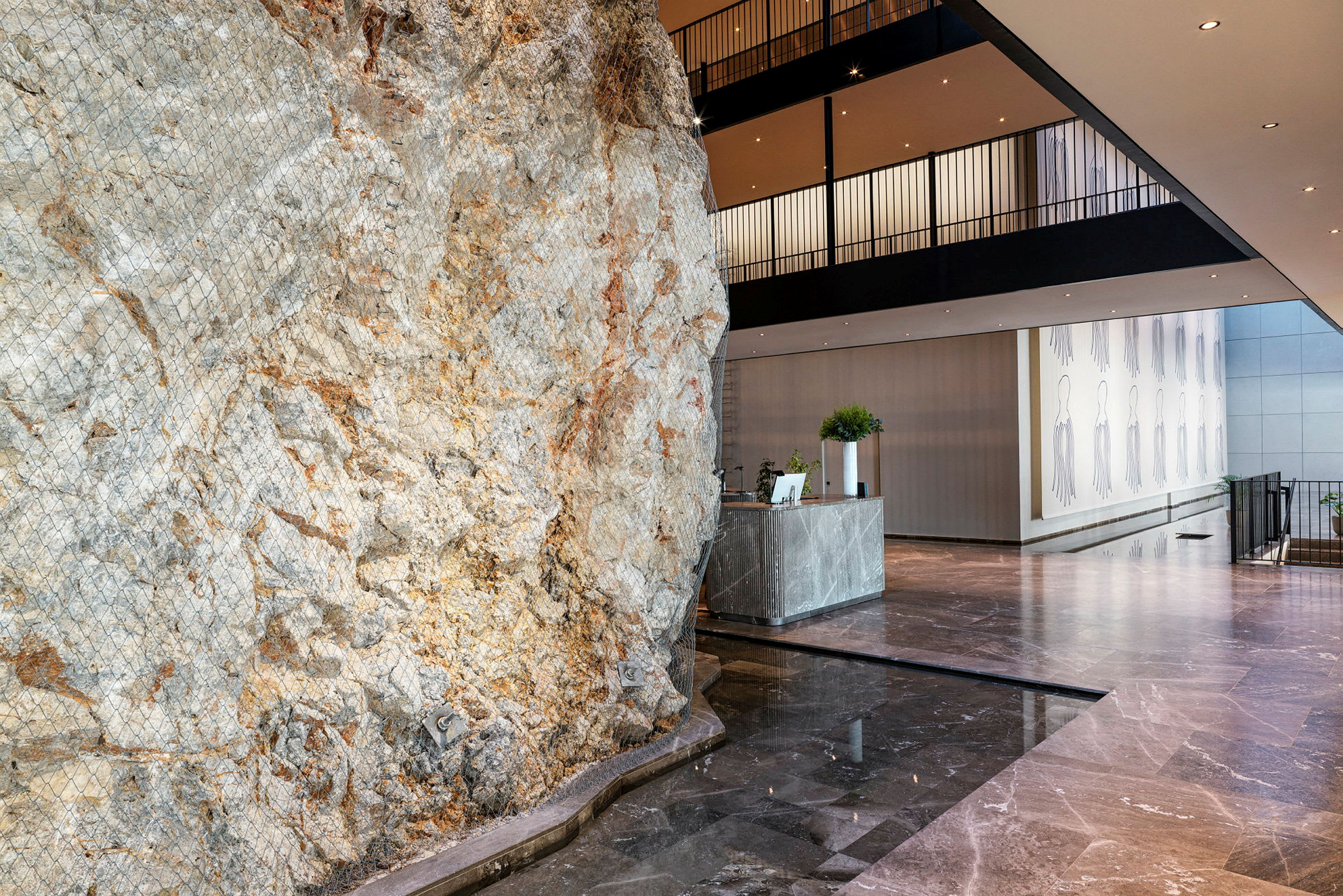 Bilden visar en hotellreception med en stor, naturlig klippvägg som en del av inredningen. (AI-genererad text)