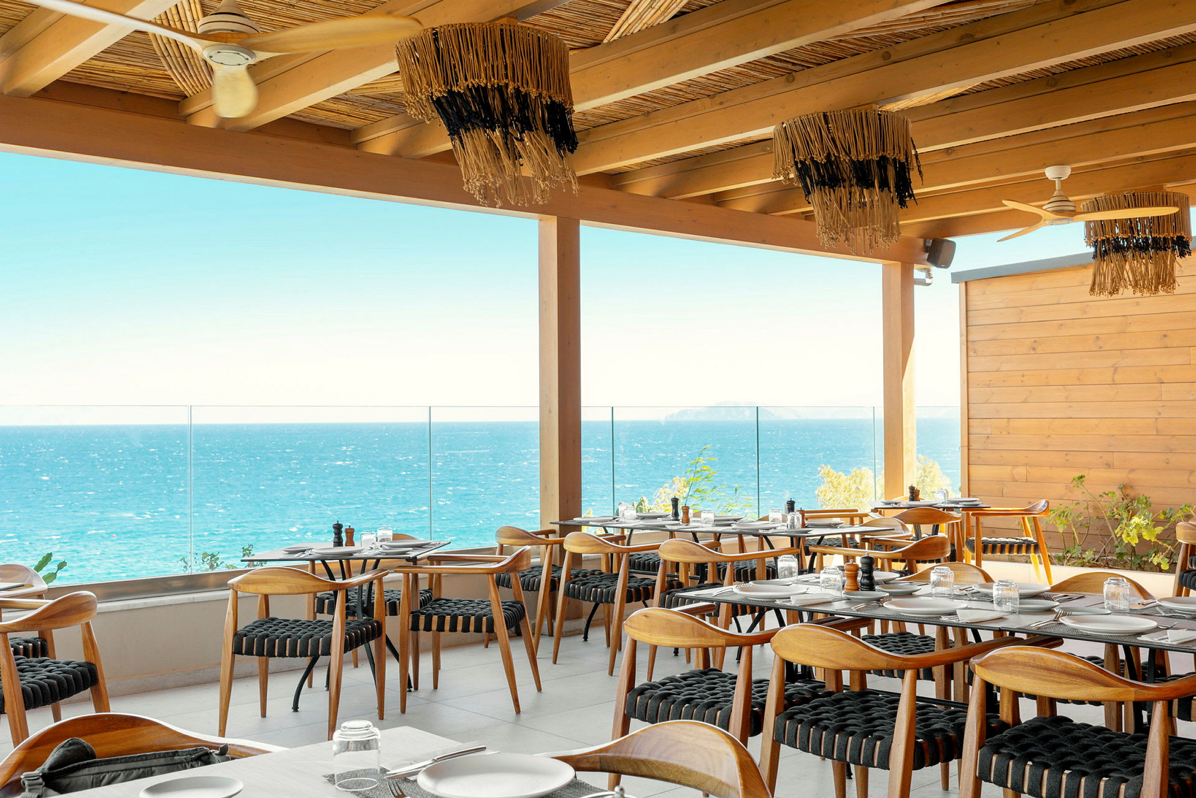 Restaurang med trämöbler och havsutsikt från en terrass. (AI-genererad text)