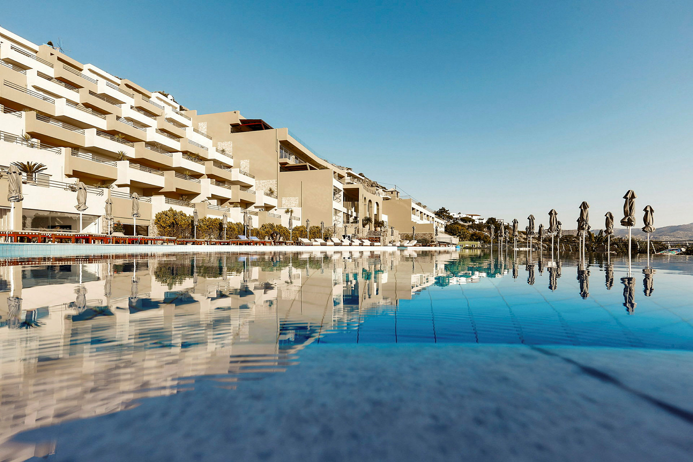 Bild av en modern hotell-byggnad med pool och solstolar. (AI-genererad text)