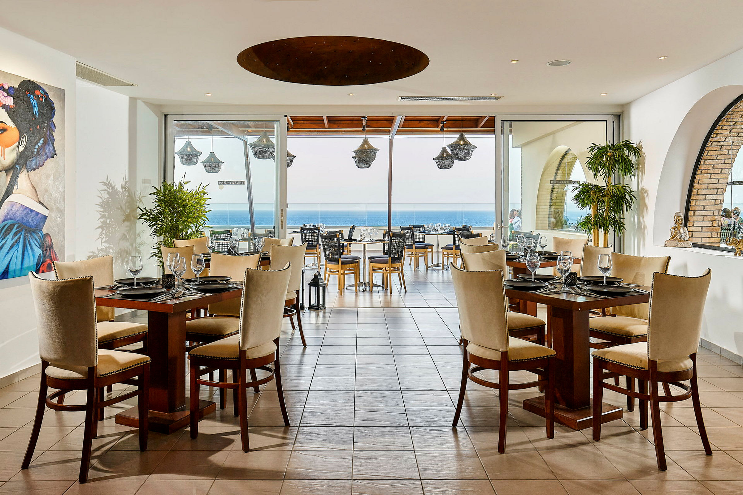 Restaurang med dukade bord och havsutsikt genom stora fönster. (AI-genererad text)