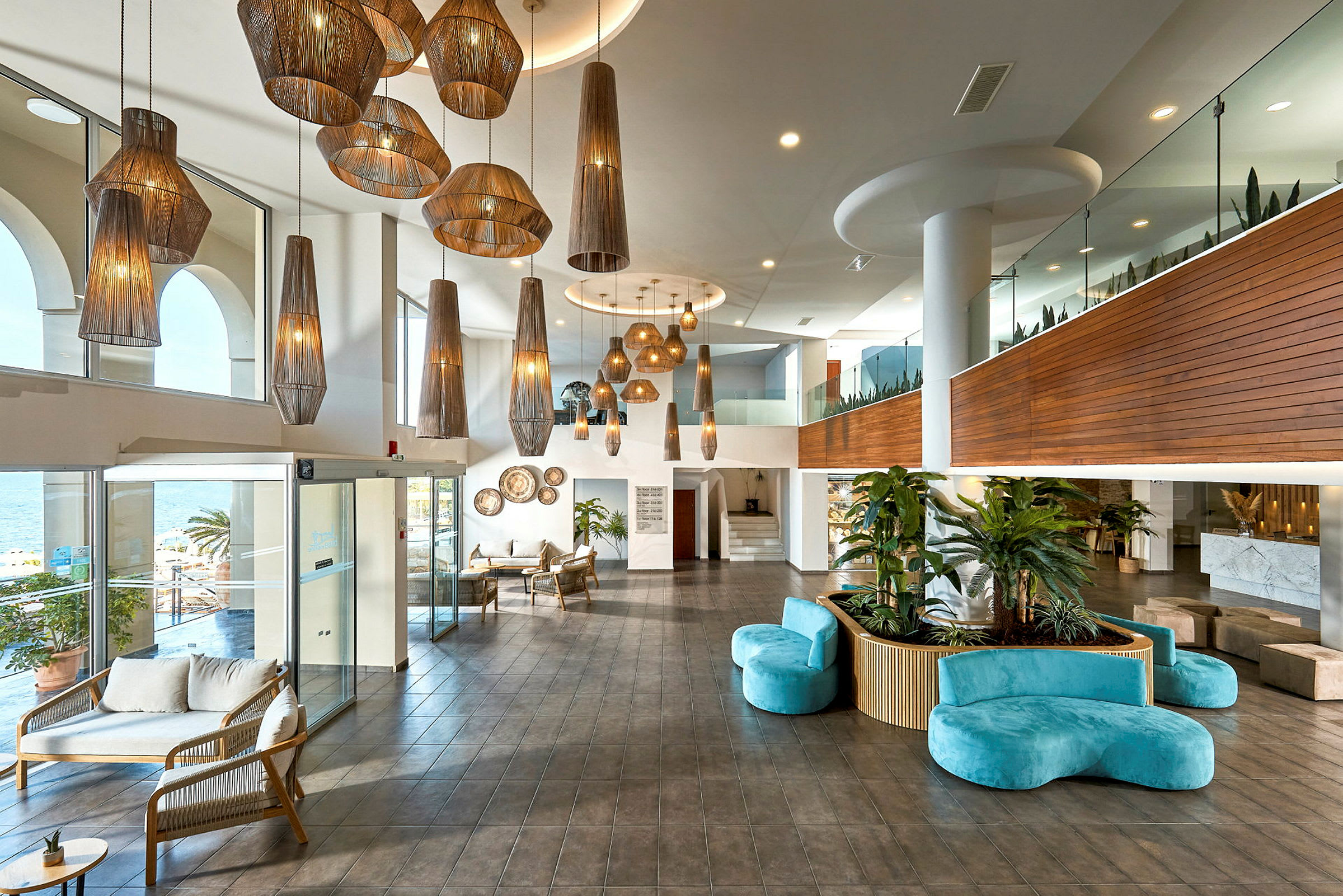 En modern hotellobby med stora hängande lampor, sittmöbler och gröna växter. (AI-genererad text)