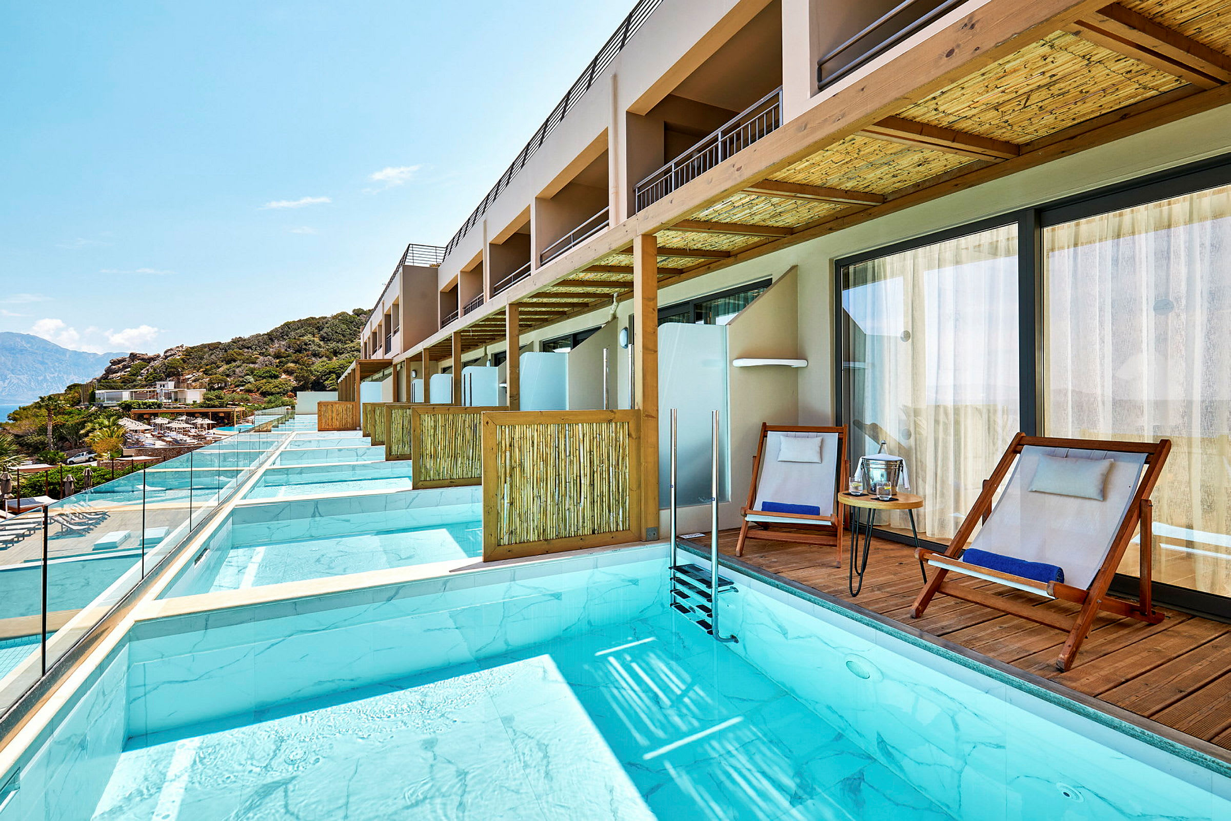 Privat poolområde med solstolar vid en rad av hotellrum. (AI-genererad text)