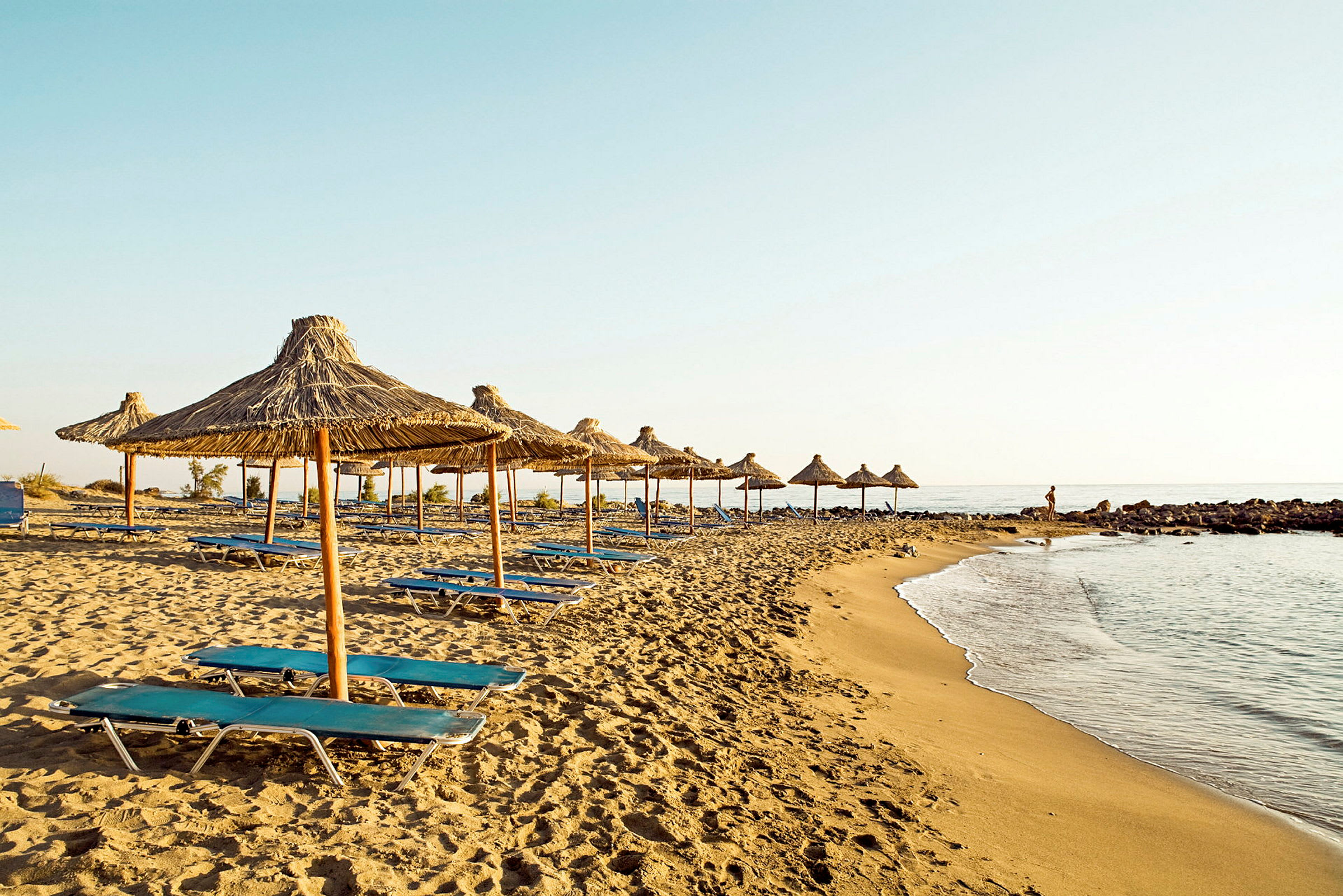 Strand med solstolar och parasoller av halm. (AI-genererad text)