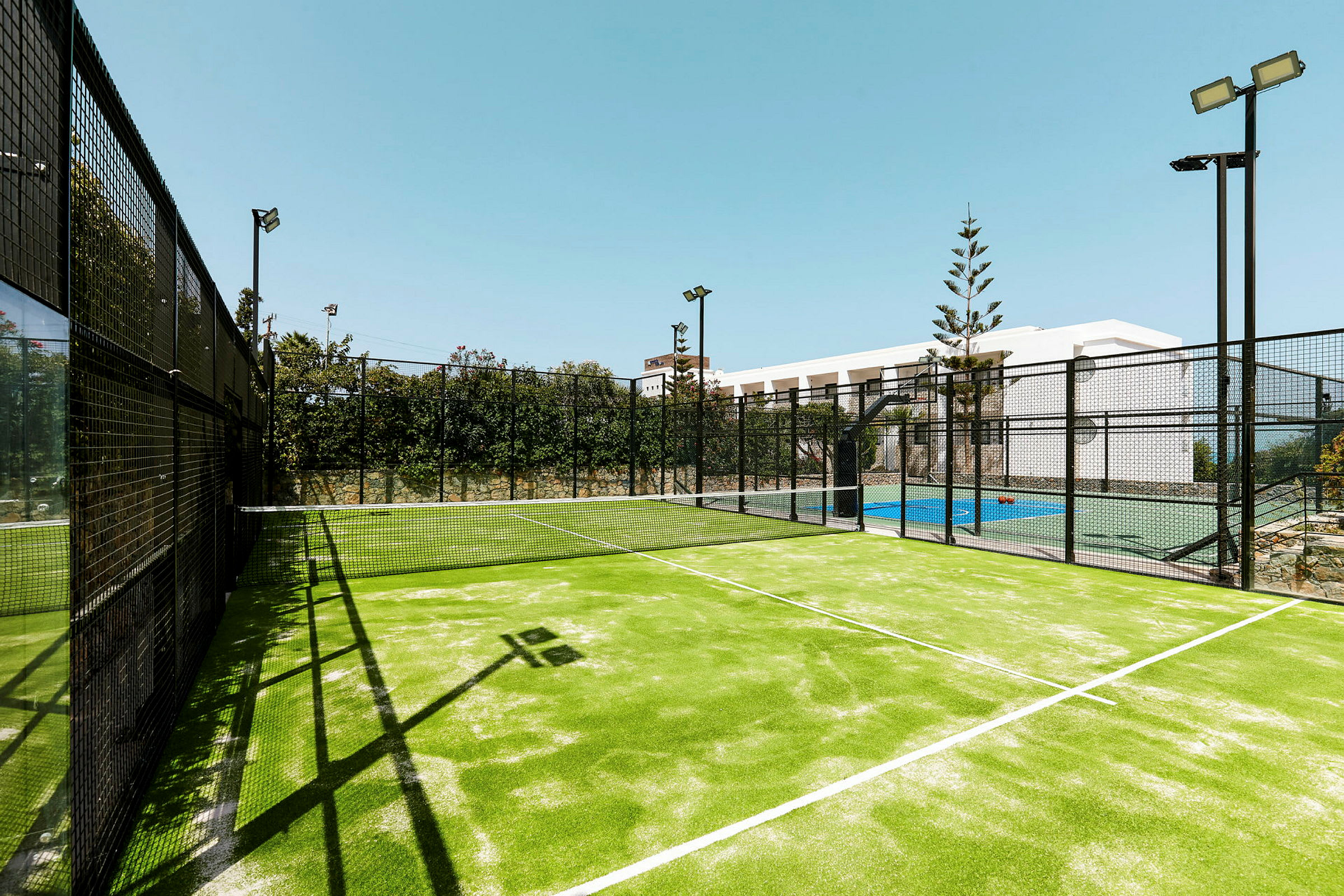 En upplyst padelbana utomhus med ett nät mellan spelplanerna. (AI-genererad text)