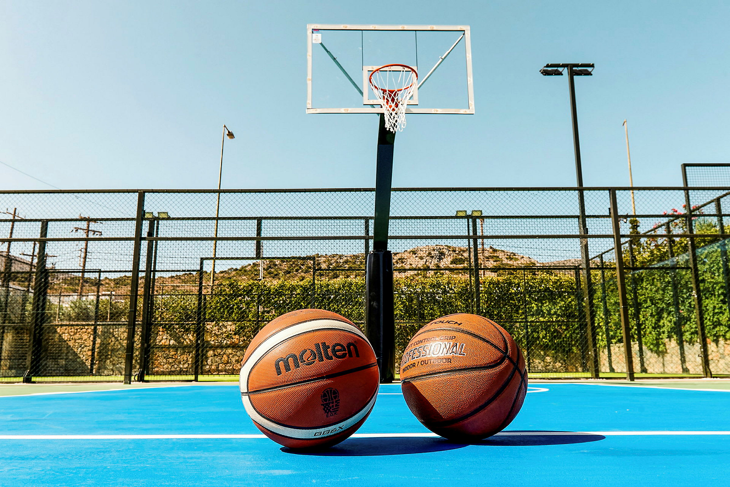 Två basketbollar på en baskerbollsplan framför en basketkorg. (AI-genererad text)
