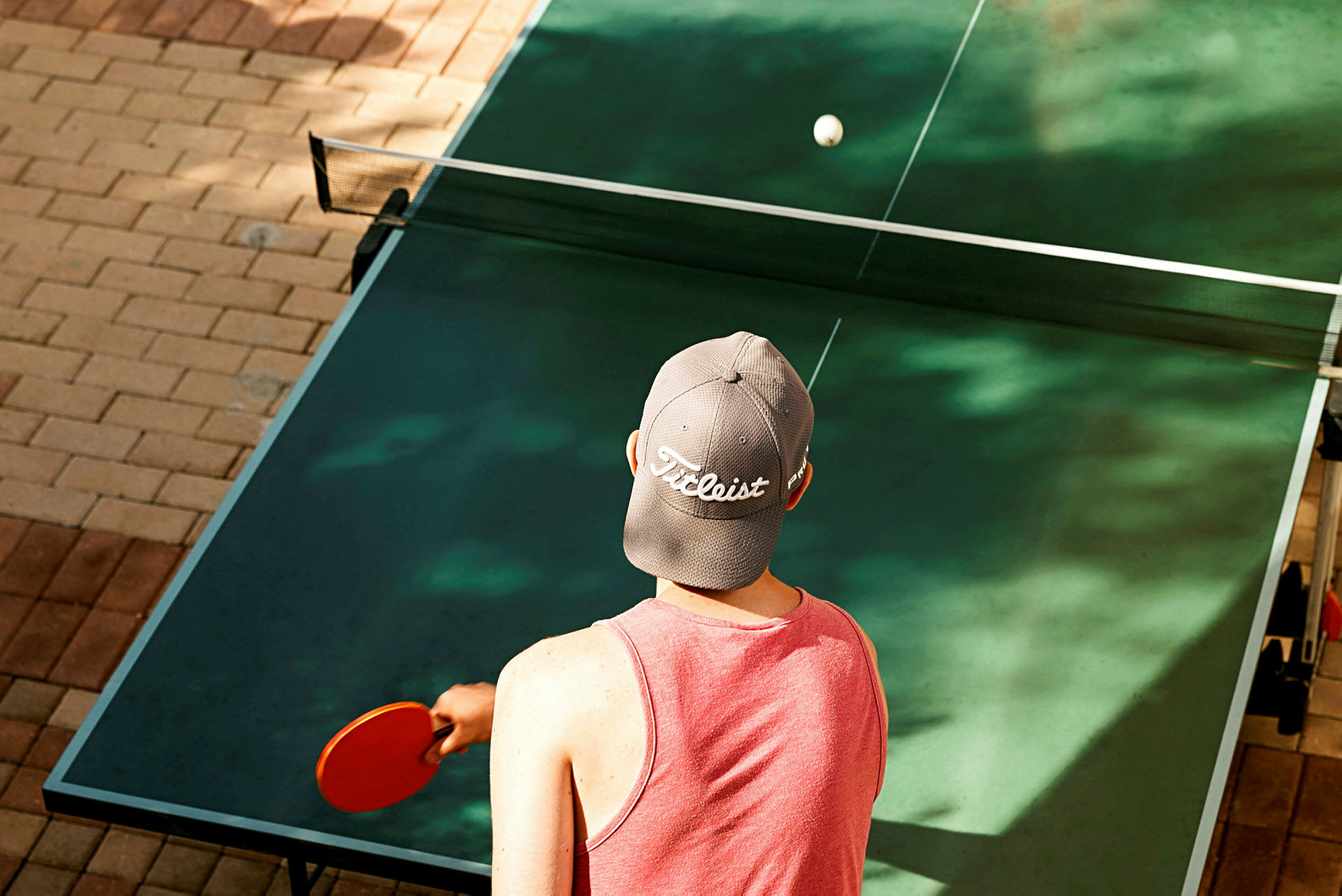 Person spelar bordtennis med en röd racket. (AI-genererad text)