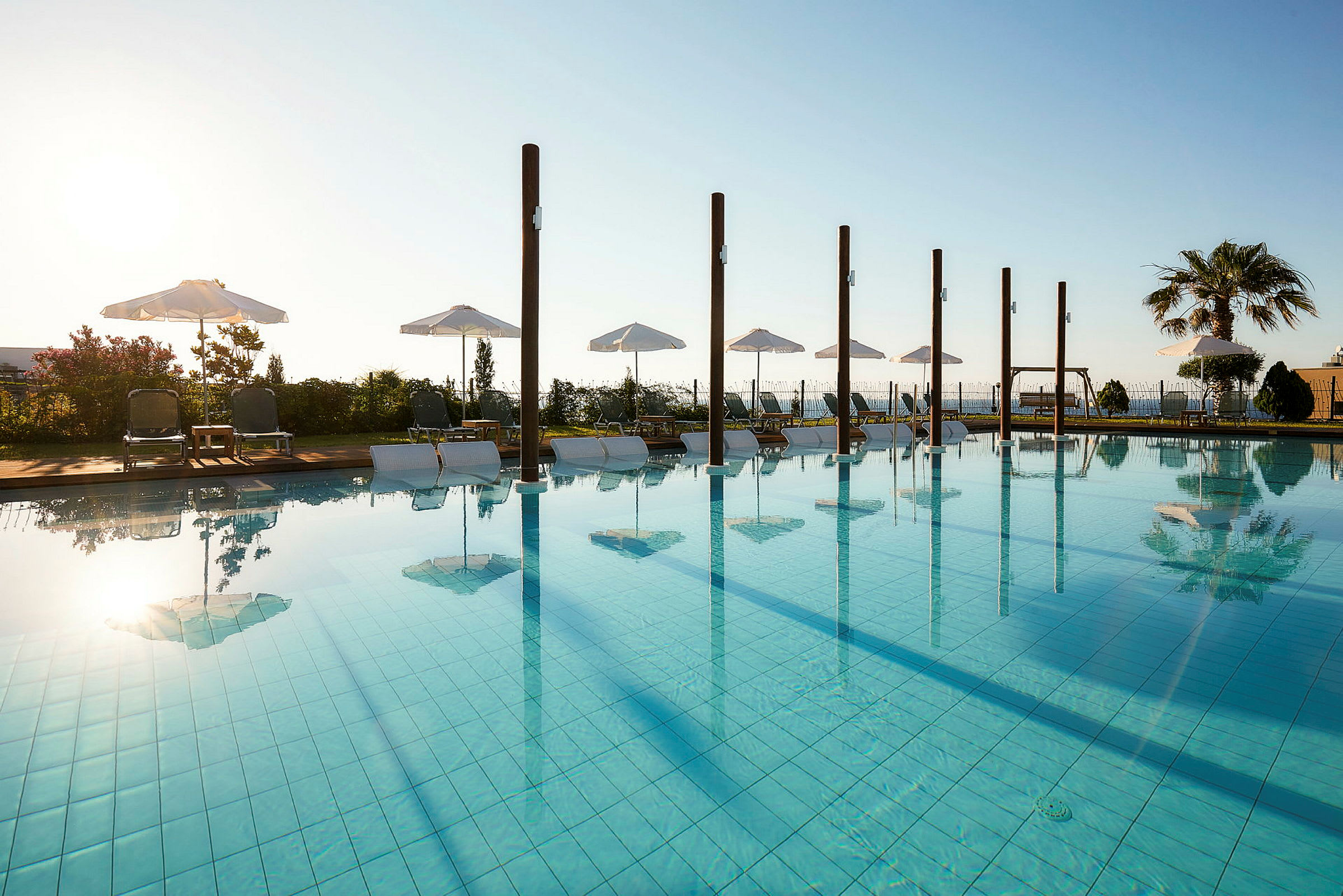 En pool med parasoller och solstolar på en solig dag. (AI-genererad text)