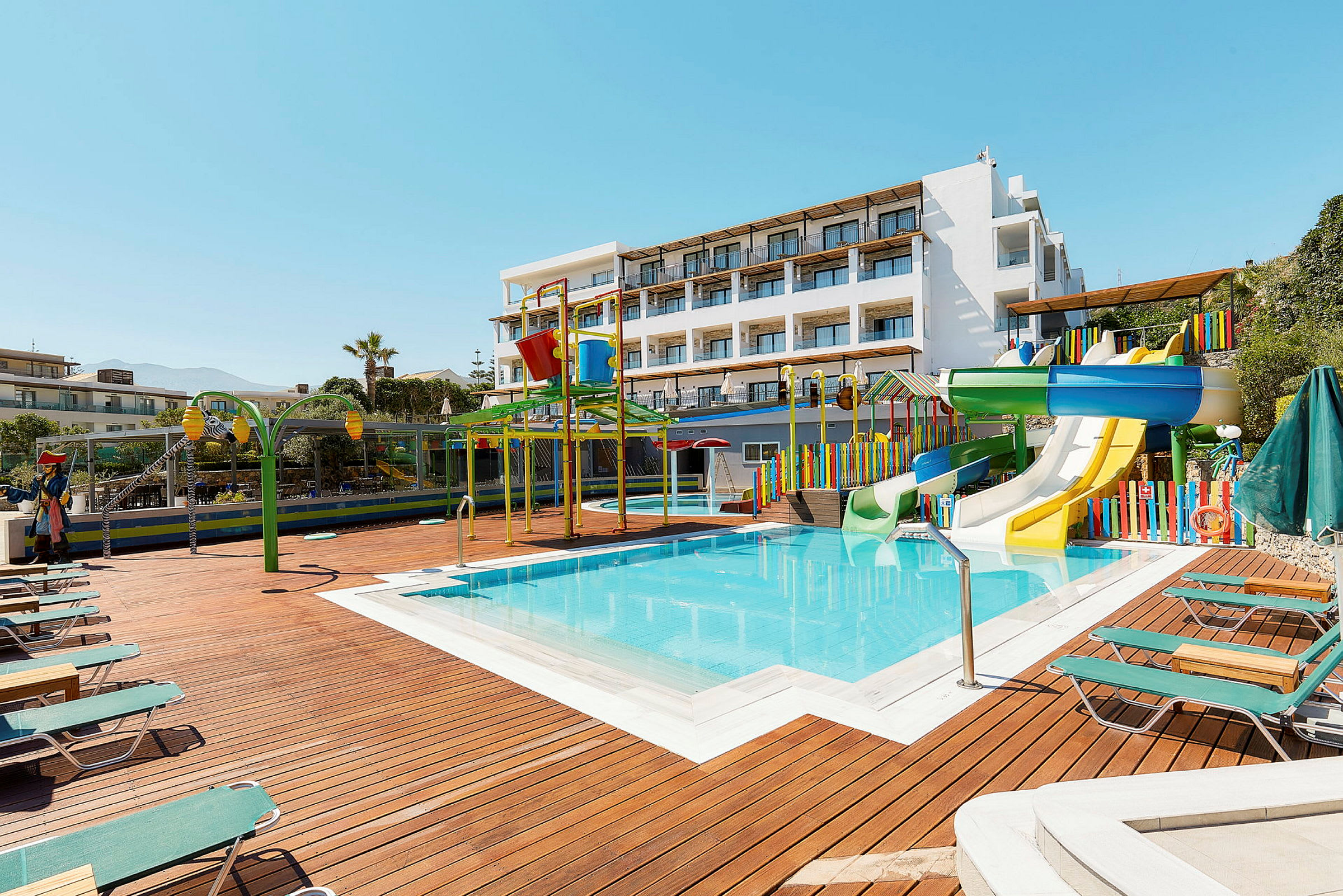 En utomhuspool med vattenrutschbanor och färgglada lekredskap vid ett hotell. (AI-genererad text)