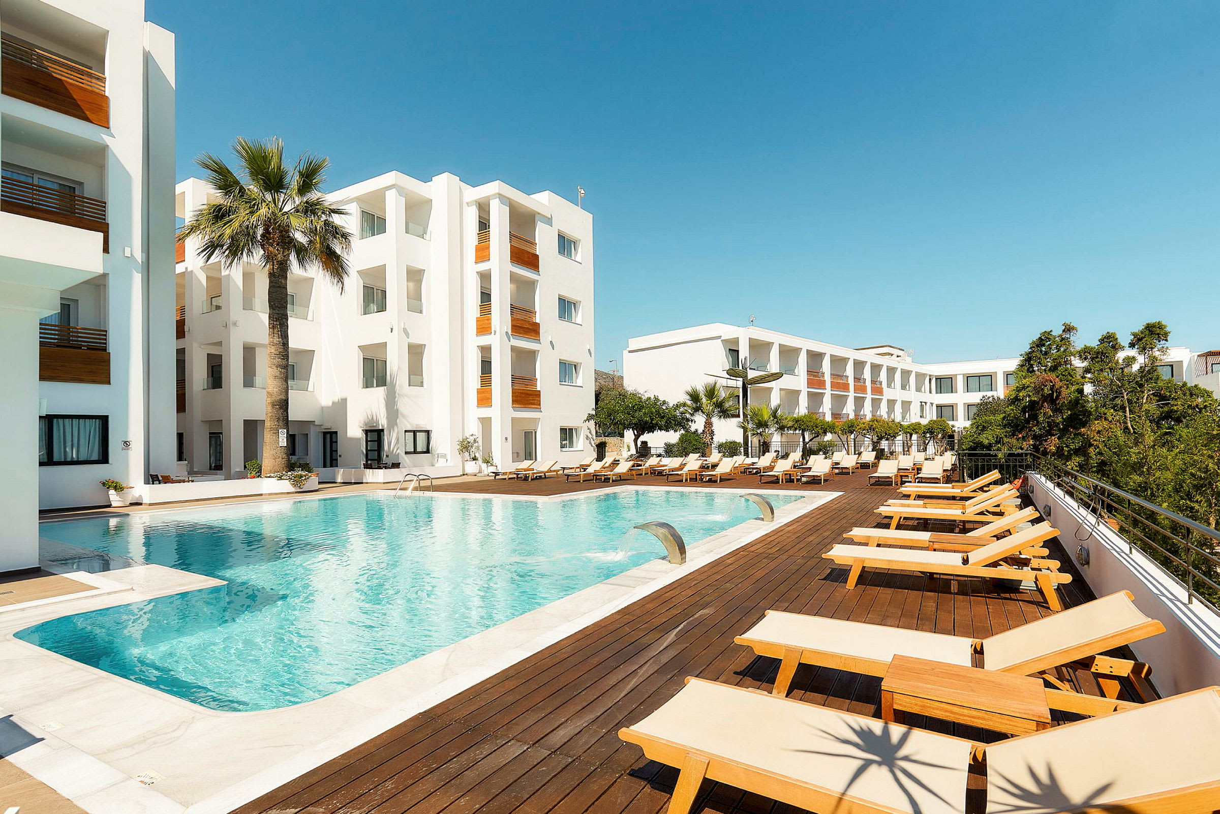 Hotellområde med swimmingpool och solstolar. (AI-genererad text)