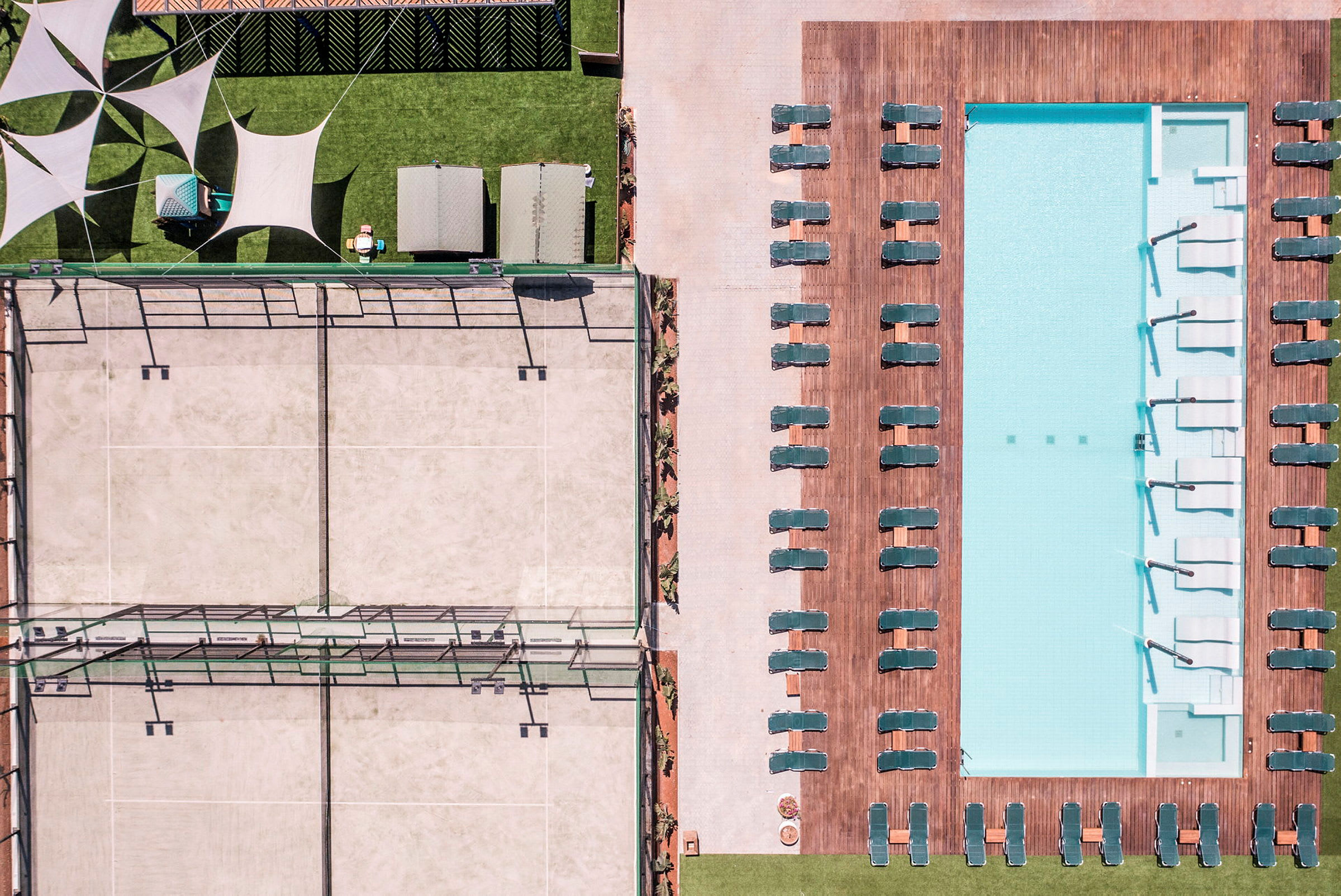 Luftbild av en pool med solstolar och en tennisbana vid sidan. (AI-genererad text)