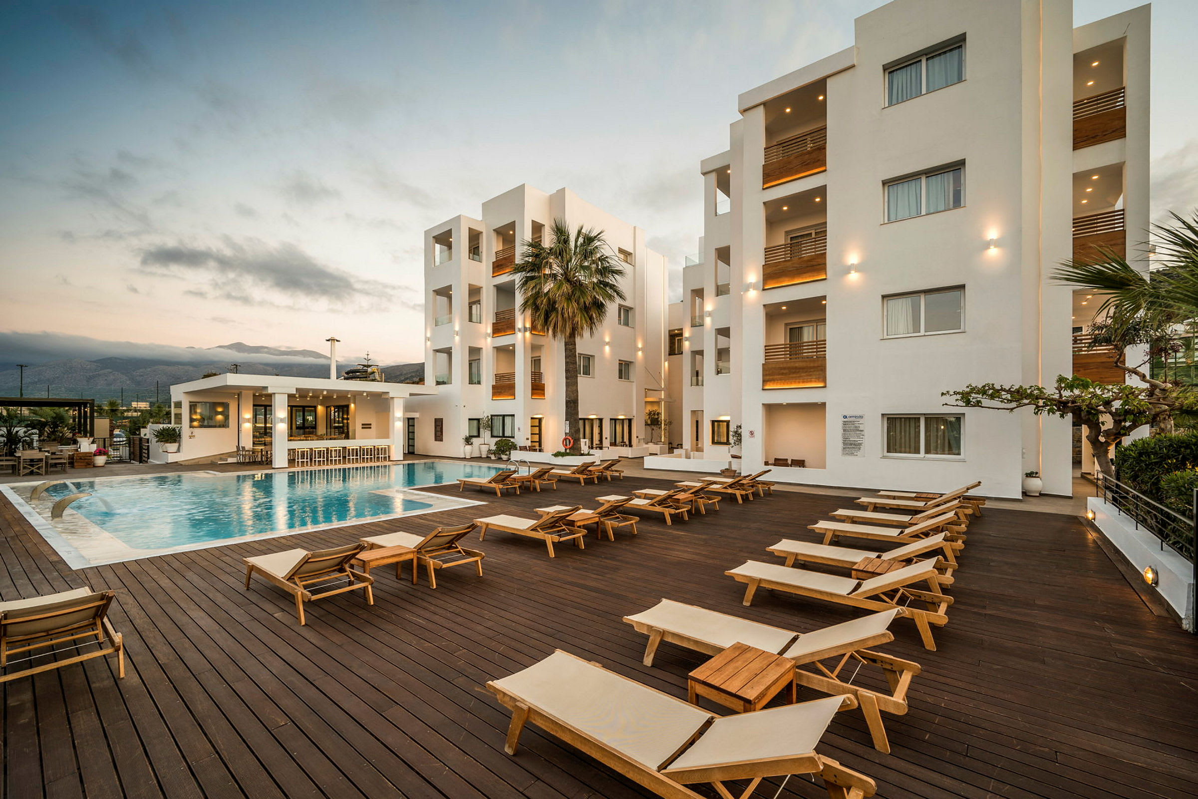 Utomhusområde med pool, solstolar och vita moderna byggnader i bakgrunden. (AI-genererad text)