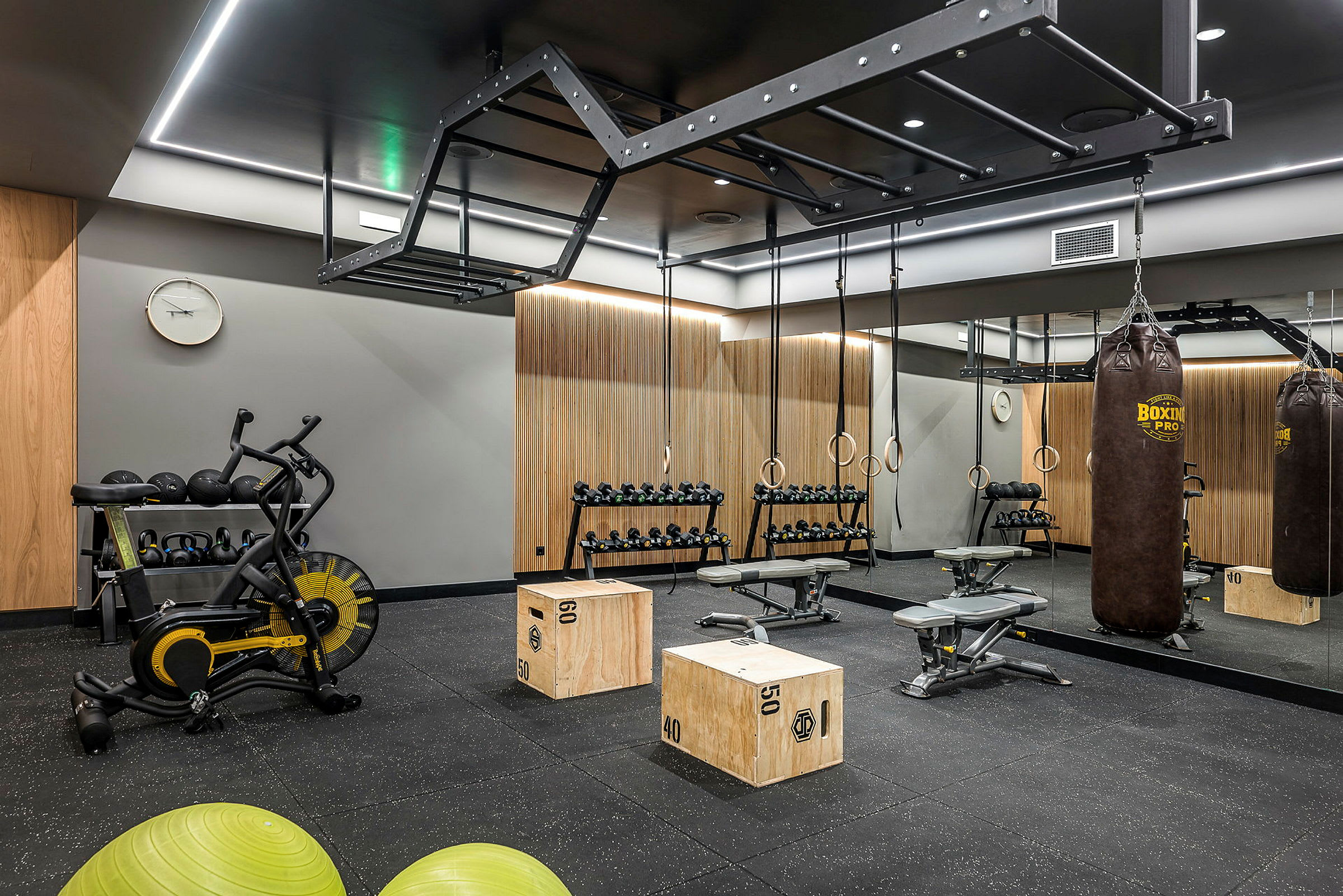 Ett gym med träningsutrustning, inklusive boxningssäck, hantlar och pilatesbollar. (AI-genererad text)