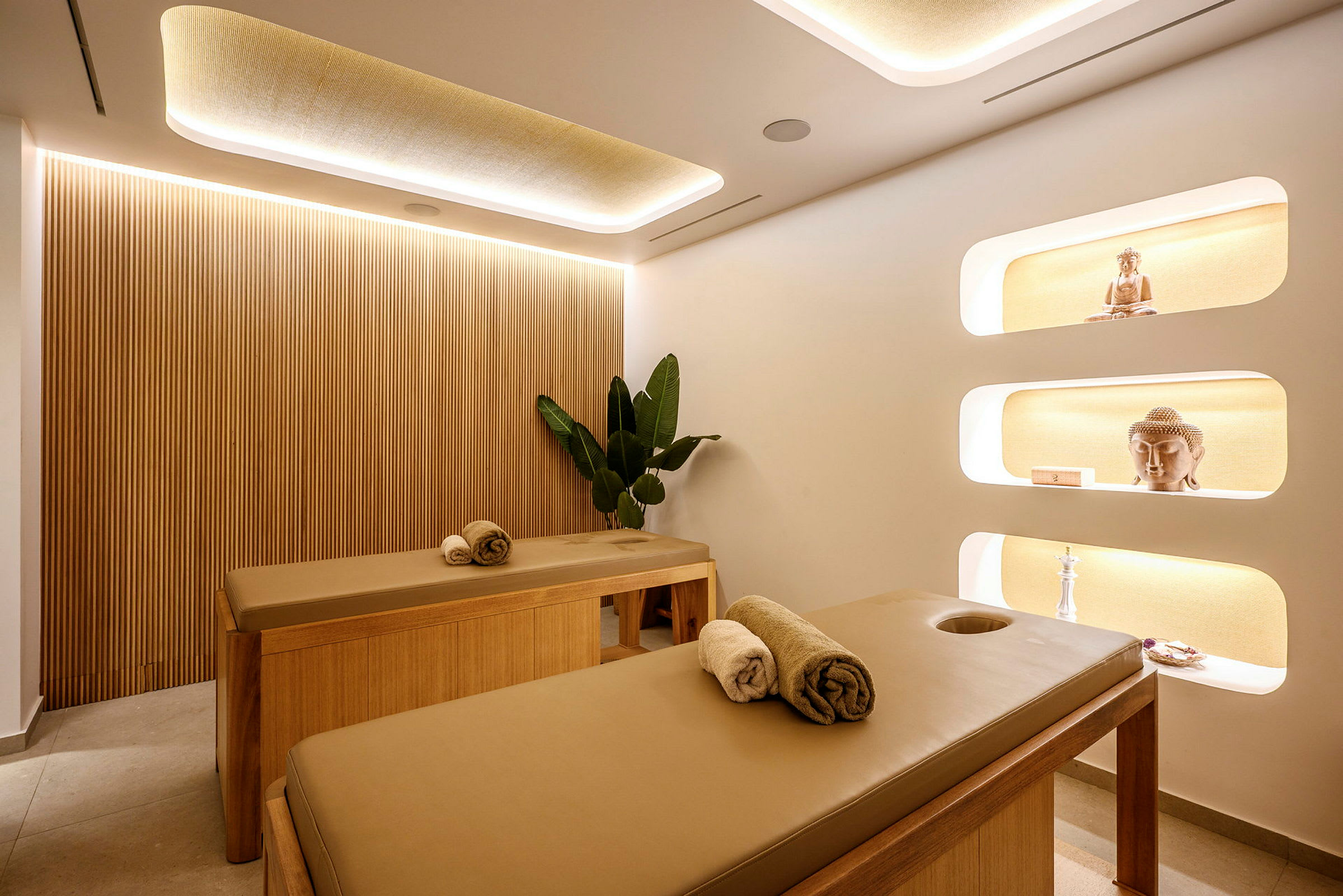 Två massagebänkar i ett elegant och välbelyst behandlingsrum. (AI-genererad text)