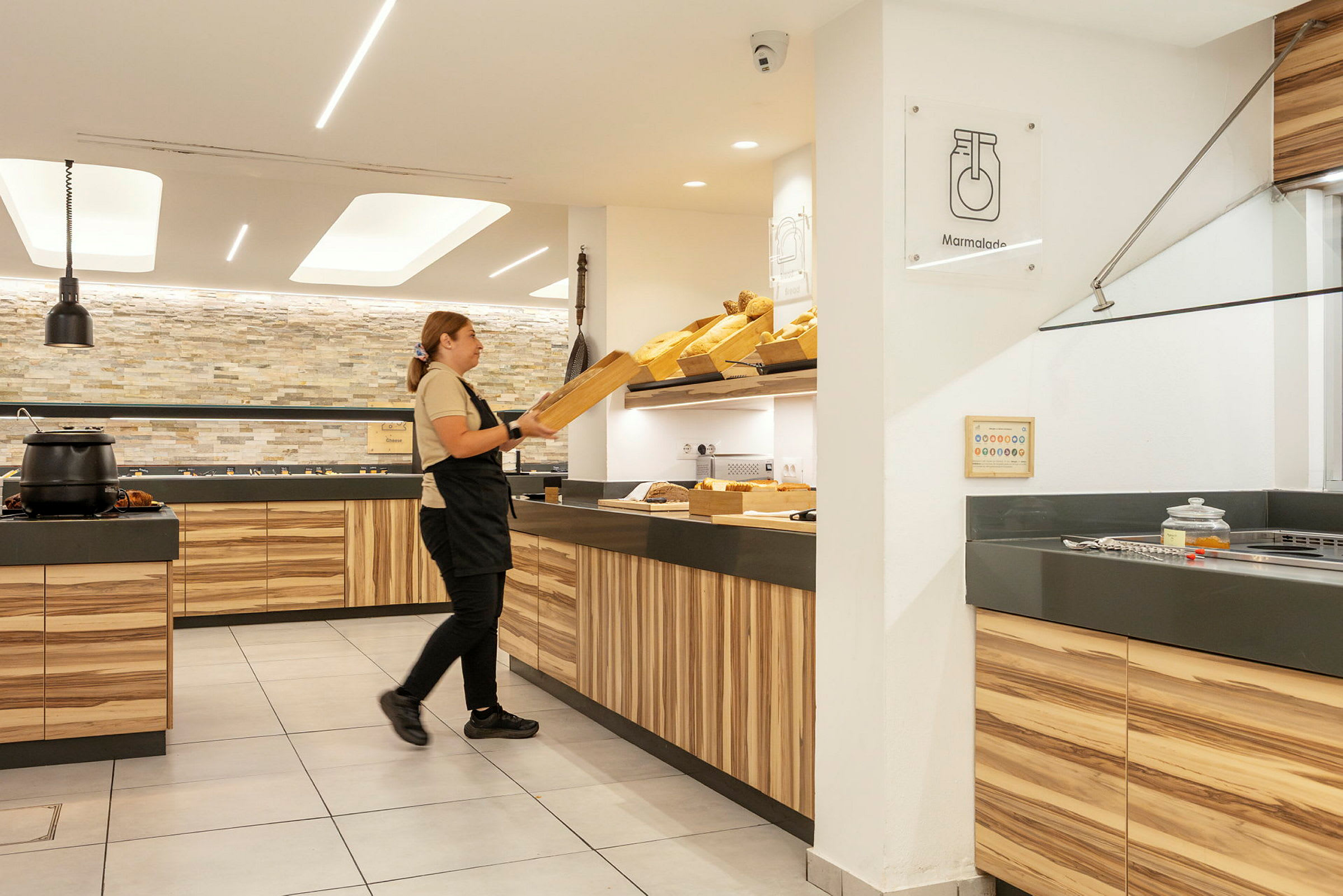 En person organiserar bröd i en ljus och modern matserveringsmiljö. (AI-genererad text)