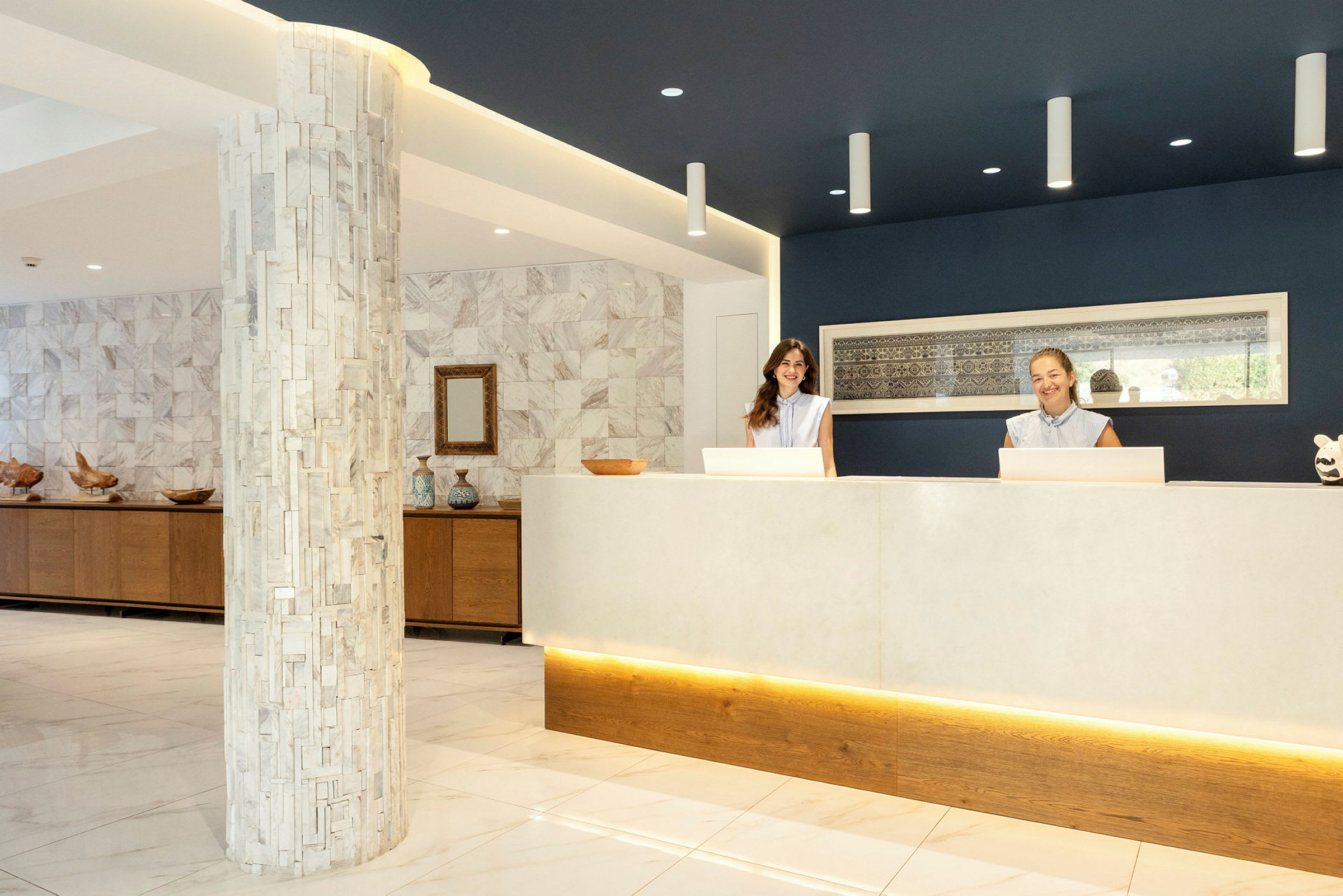 Reception med två receptionister bakom en disk. Miljön är ljus och elegant med marmordetaljer. (AI-genererad text)
