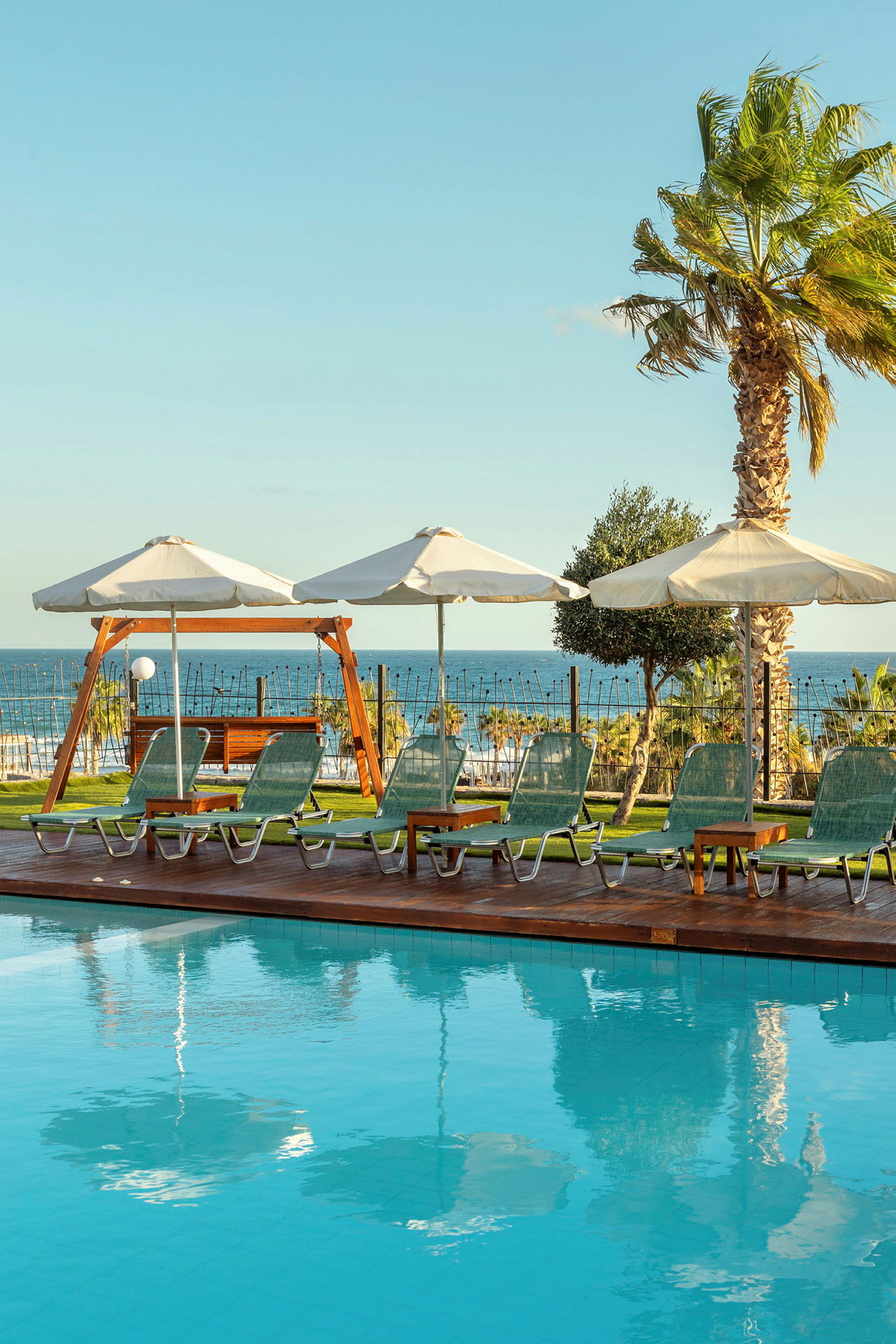 Solstolar och parasoller står vid en pool med utsikt mot havet. (AI-genererad text)