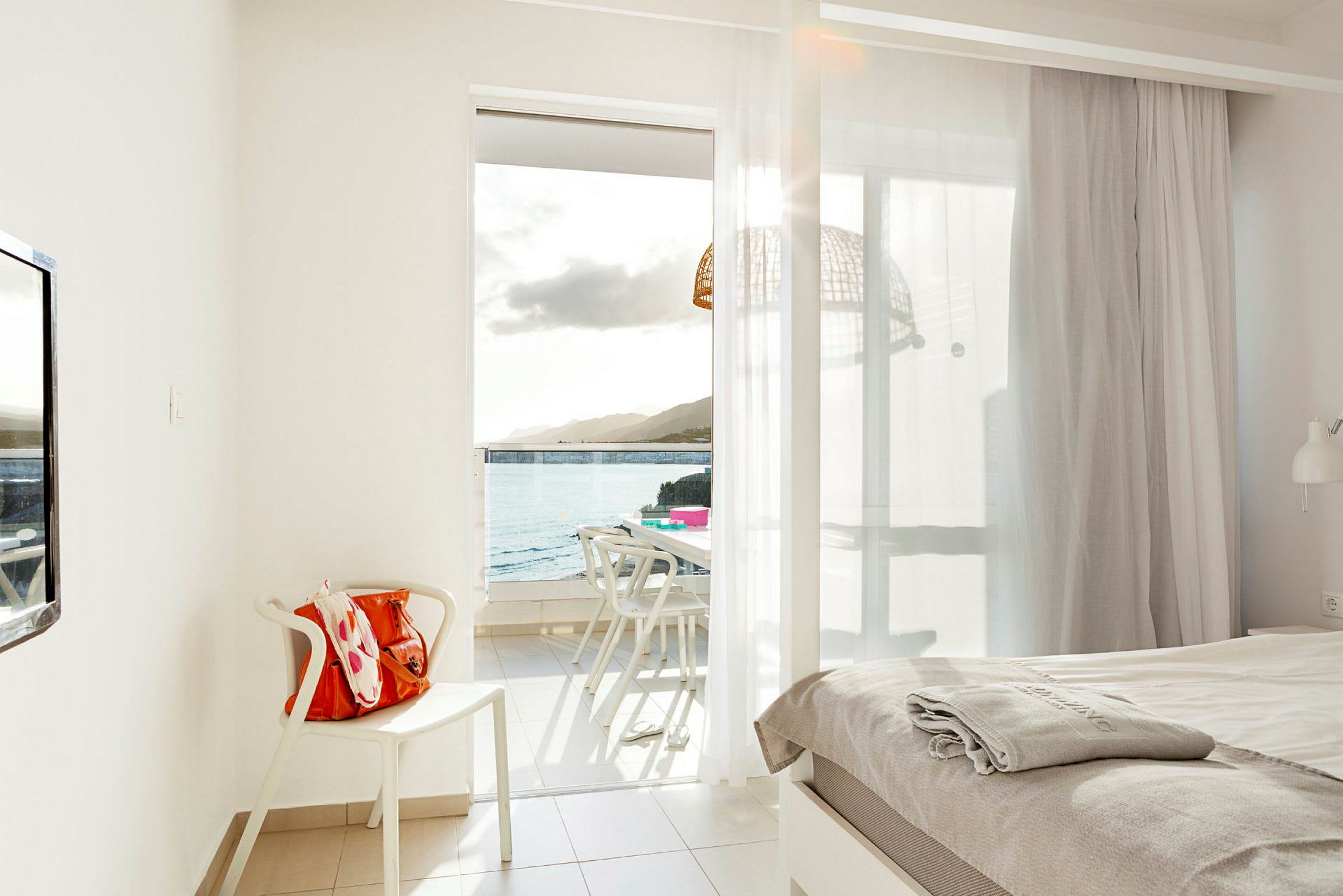 Hotellrum med utsikt mot havet genom en öppen balkongdörr. (AI-genererad text)