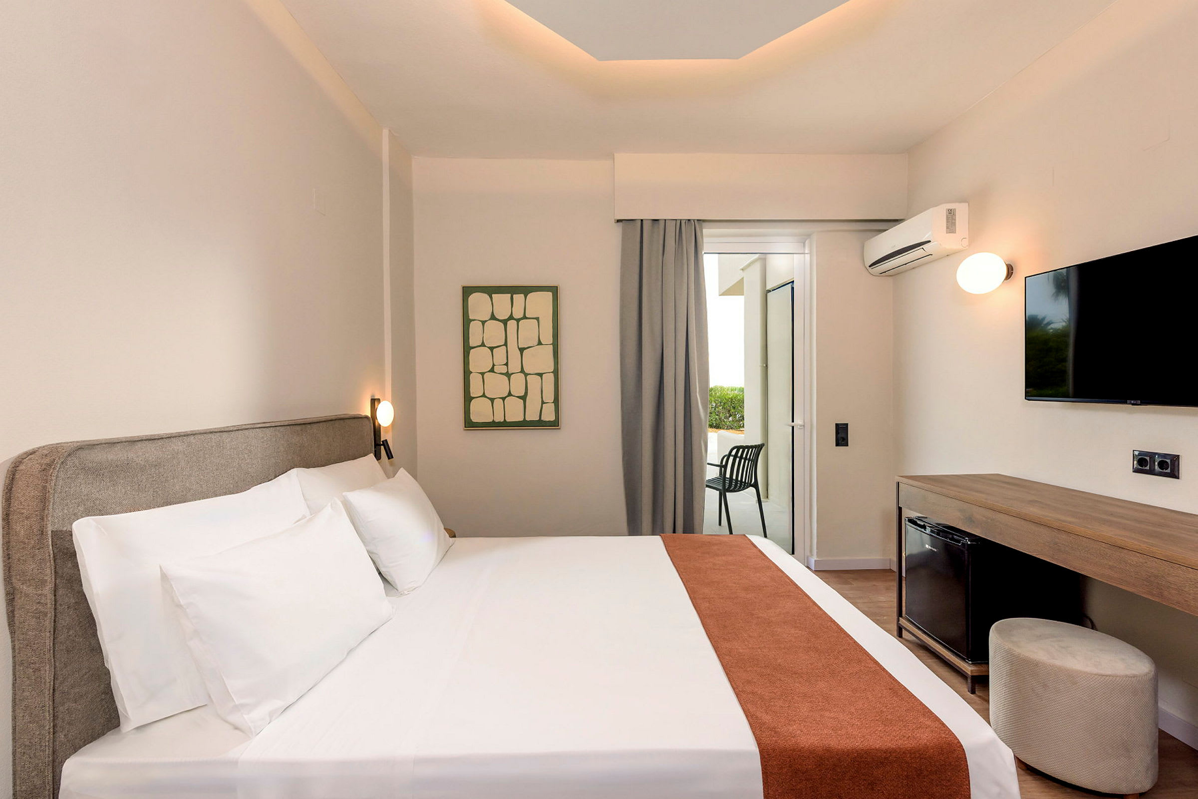 Ett hotellrum med en dubbelsäng, TV och en möblerad balkong. (AI-genererad text)