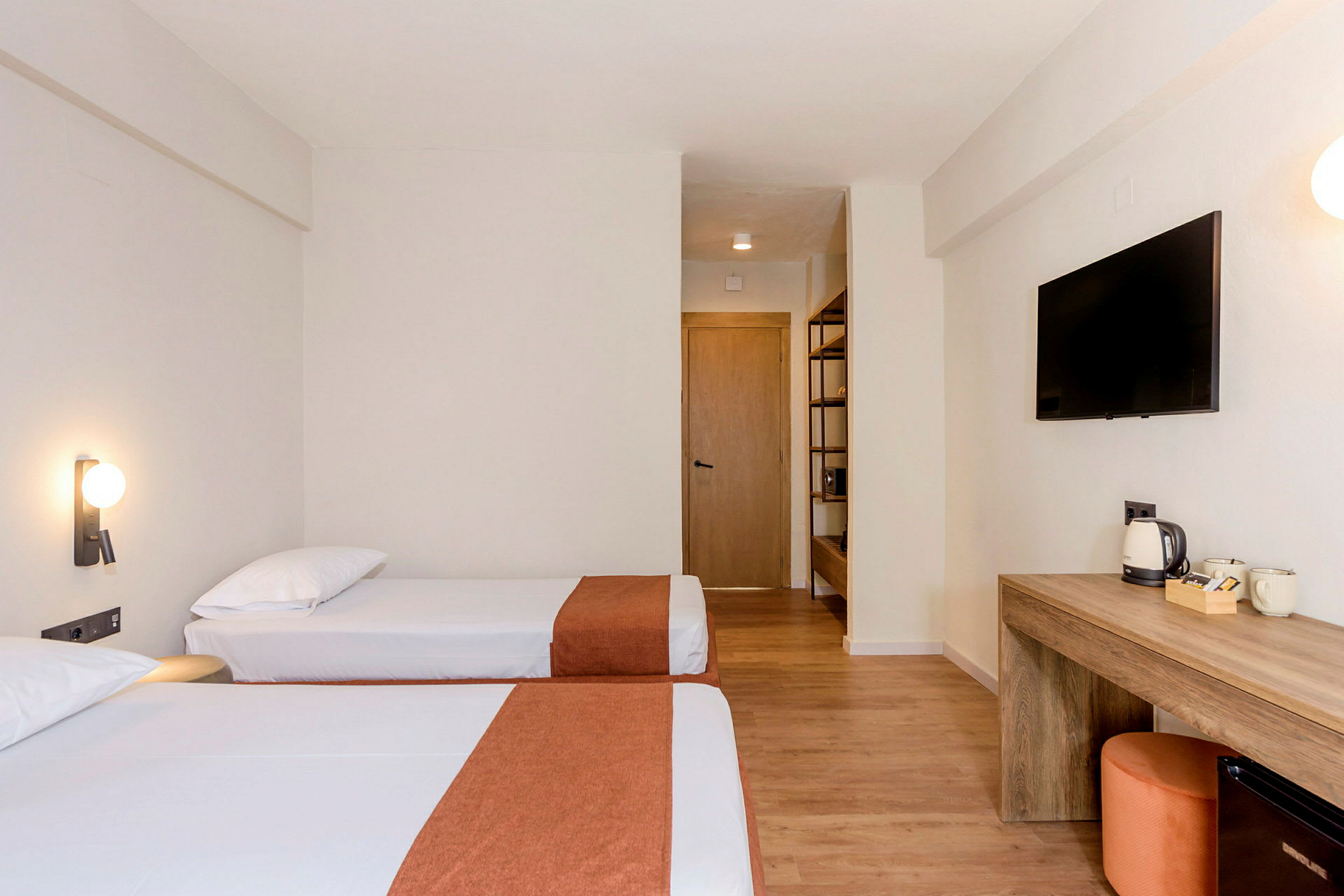 Två enkelsängar i ett hotellrum, med en skrivbordsområde och TV på väggen. (AI-genererad text)