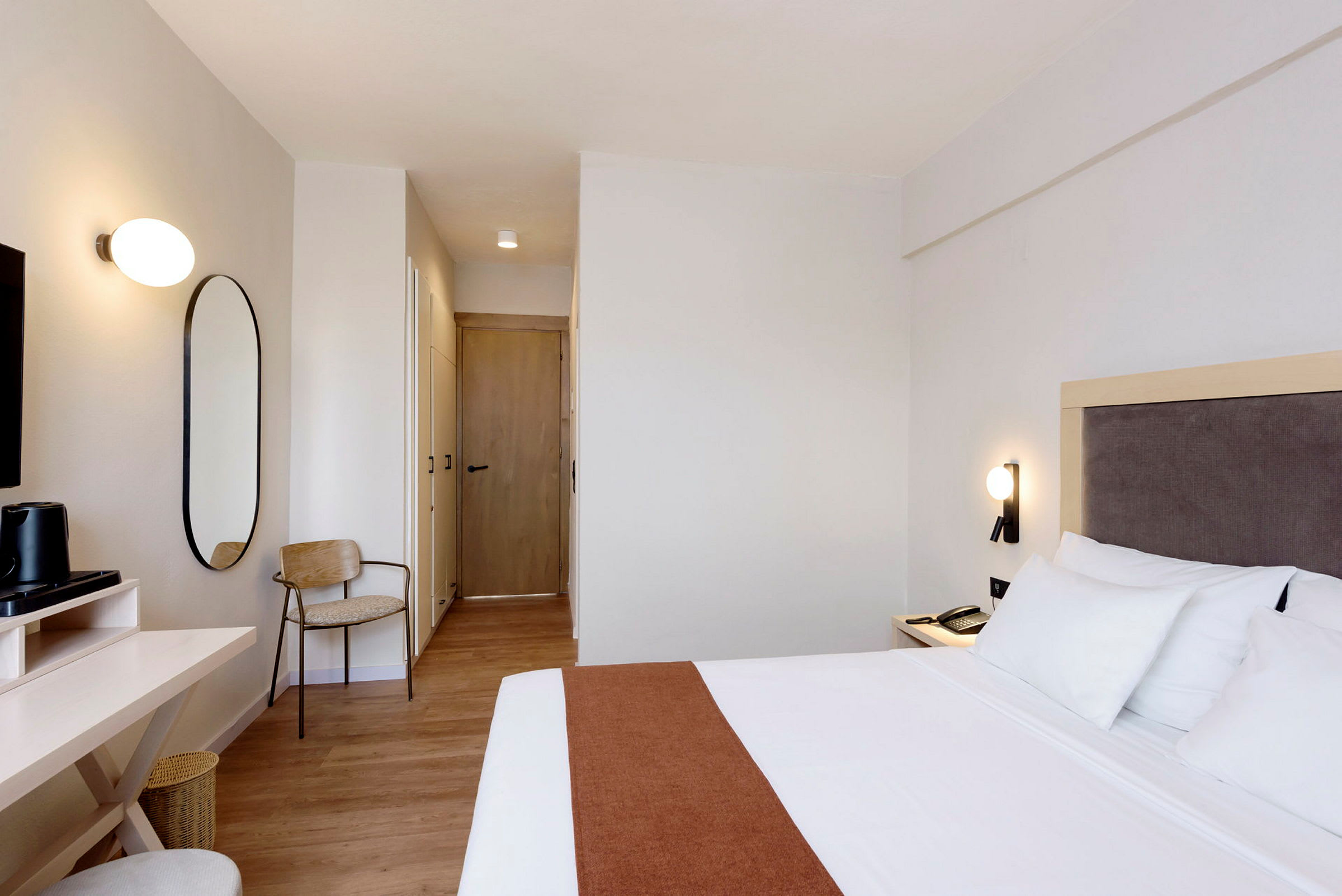 Ett hotellrum med en säng, skrivbord och stol. (AI-genererad text)
