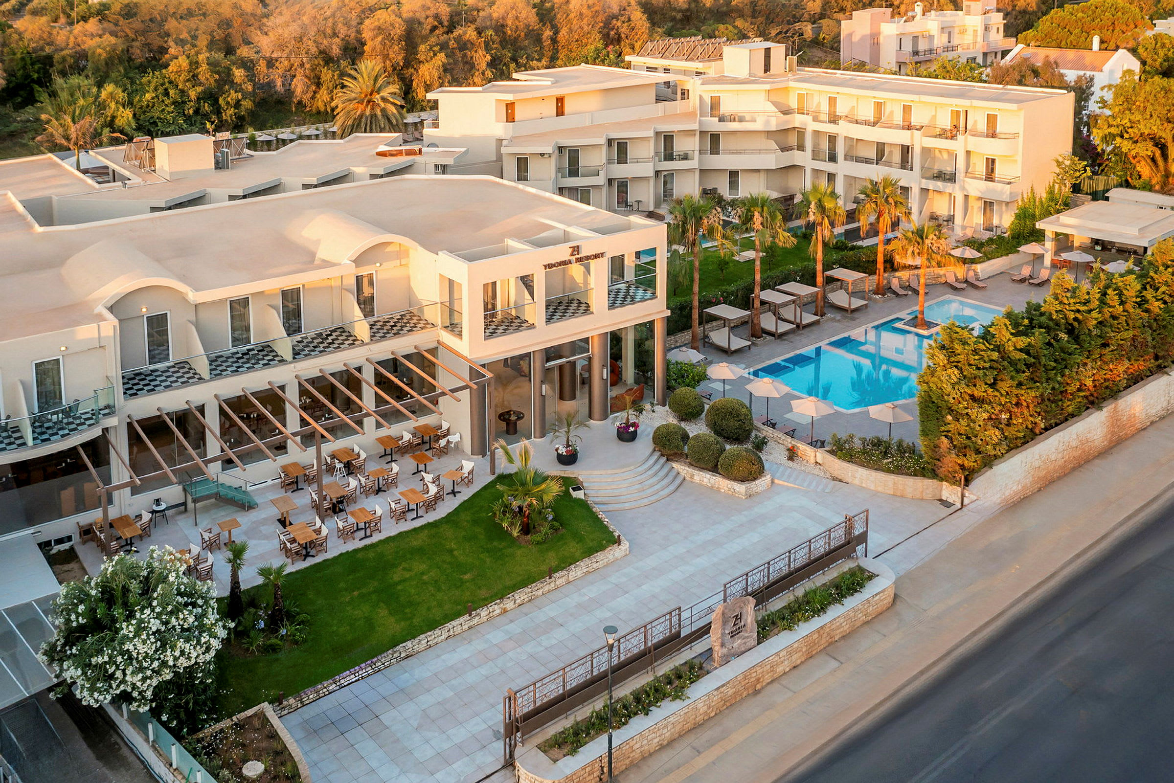 Hotellbyggnad med pool och omgivande grönska. (AI-genererad text)