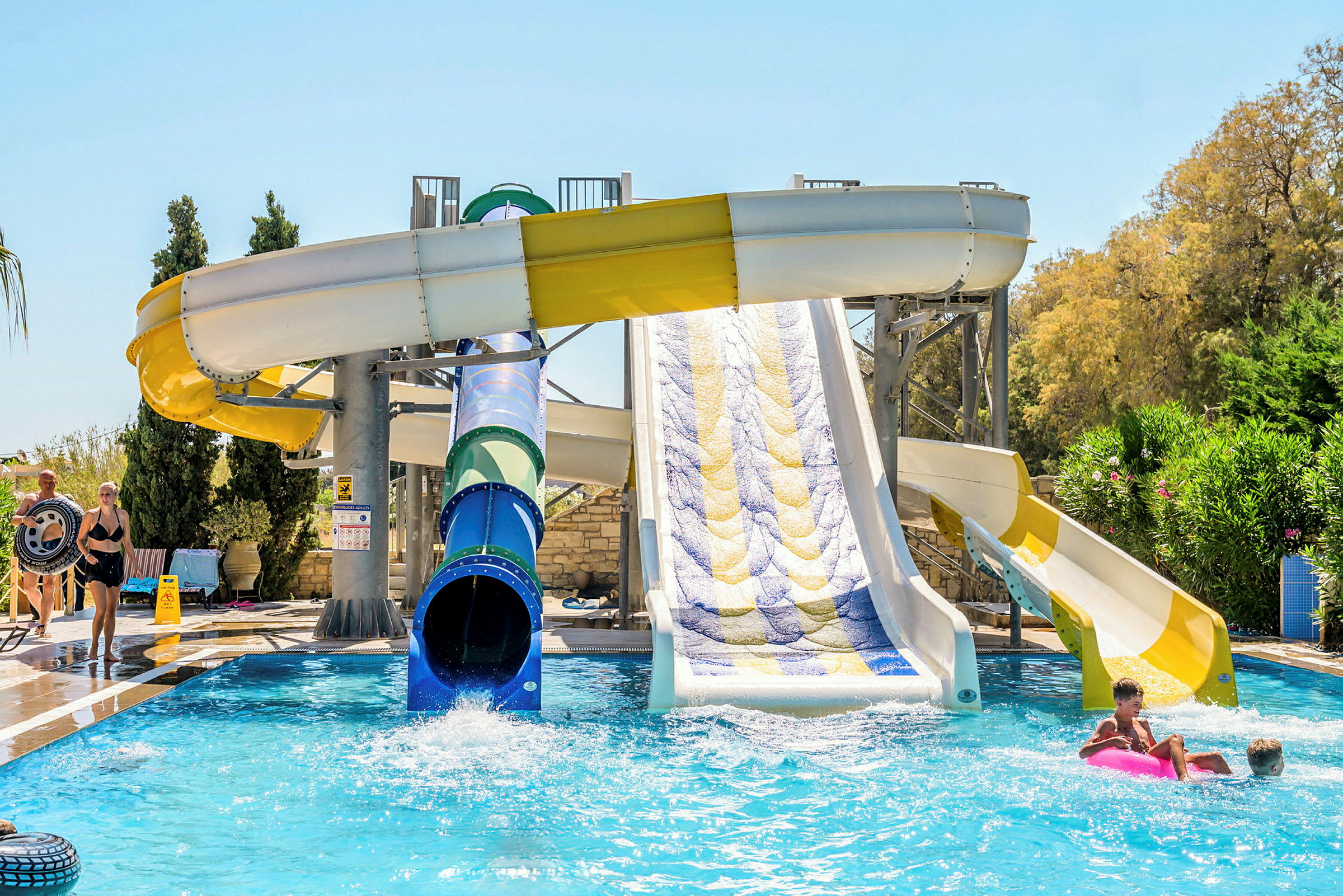 Vattenrutschbanor vid en pool omgivna av grönska. (AI-genererad text)