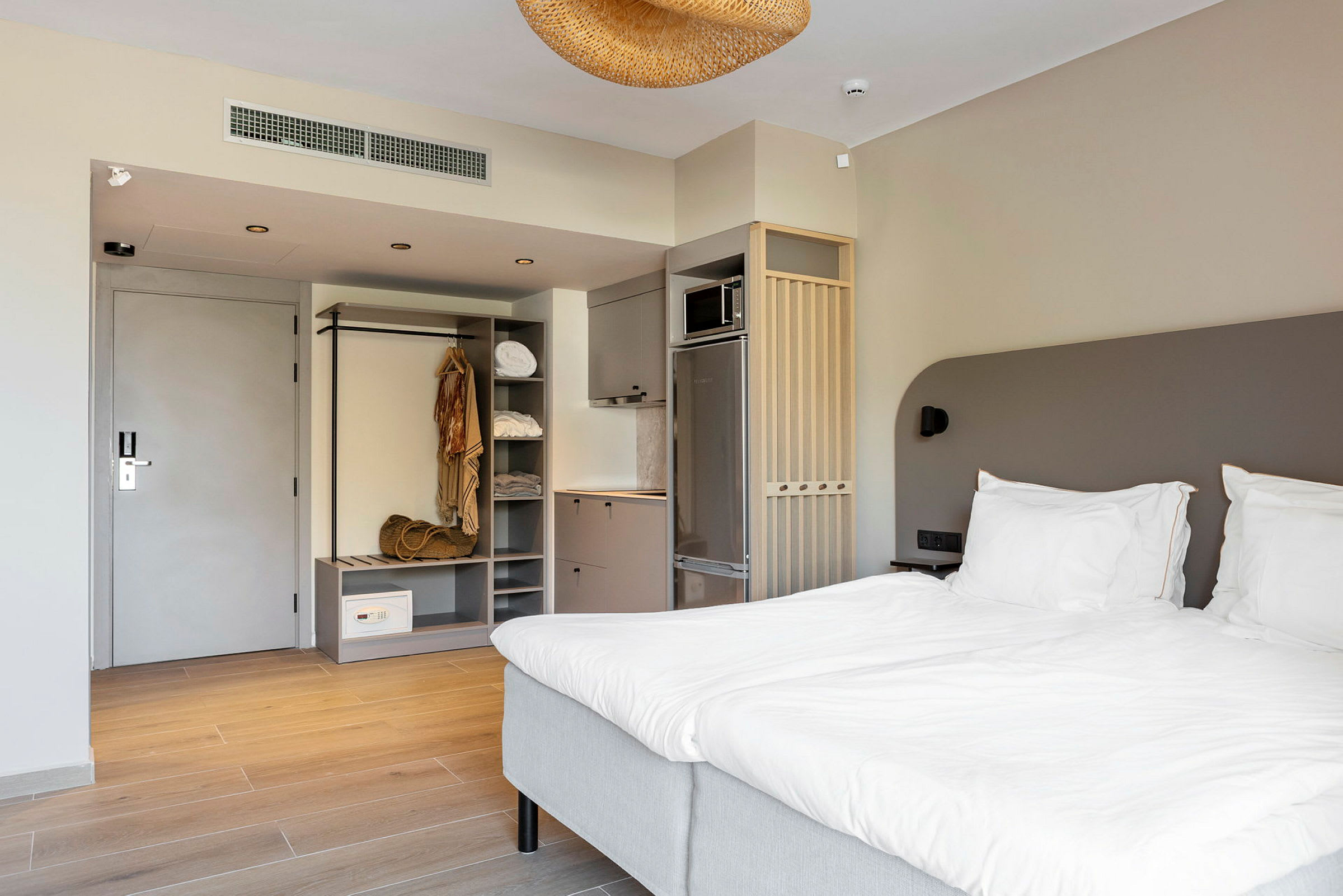 Ett hotellrum med en dubbelsäng, garderob och köksutrustning. (AI-genererad text)