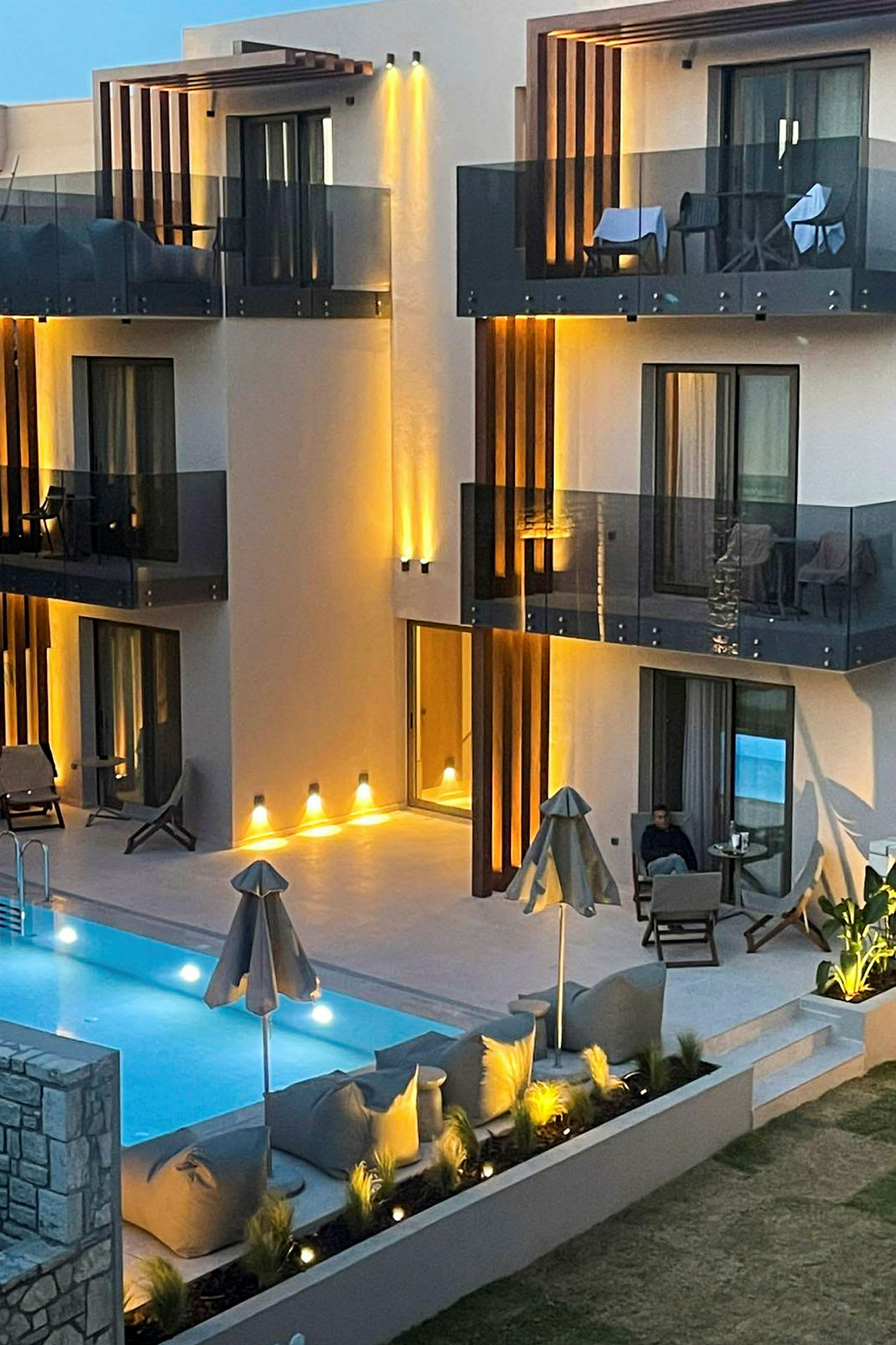 Bild av en modern byggnad med balkonger och en upplyst poolområde. (AI-genererad text)