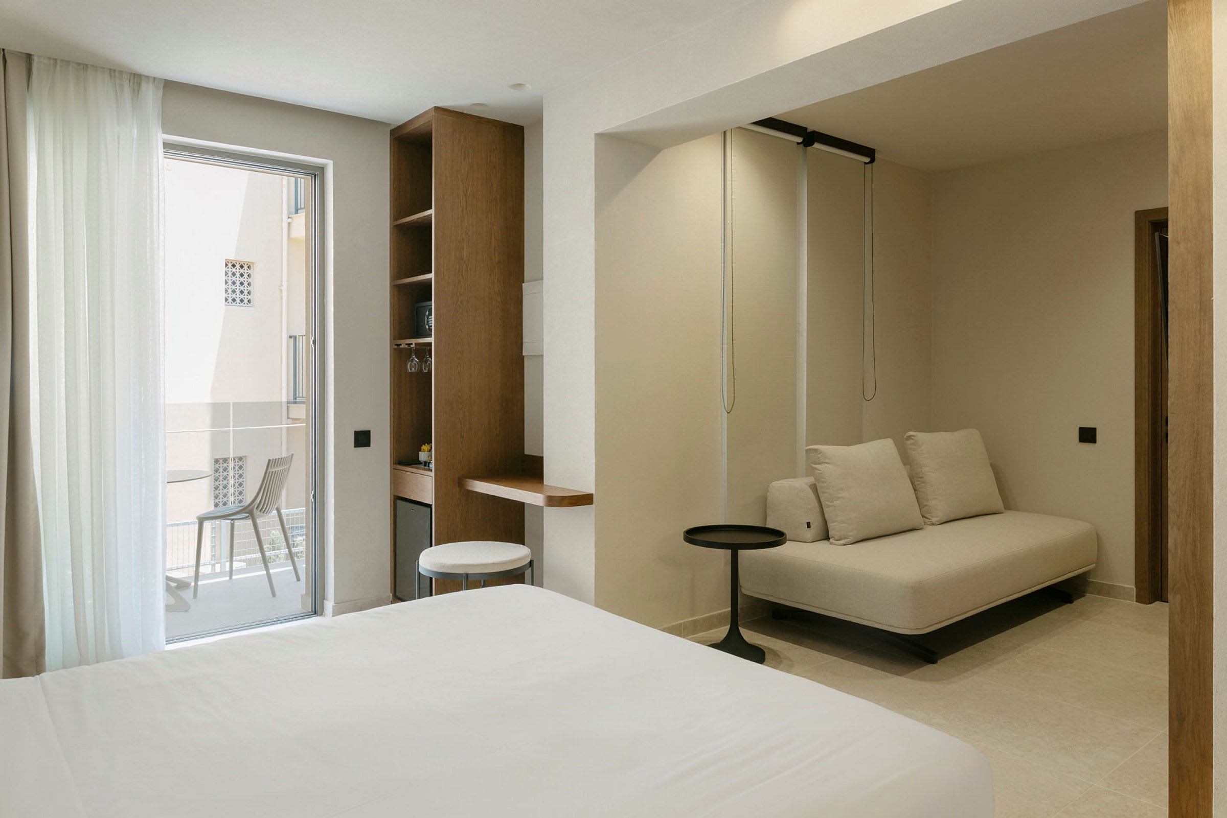 Modern hotellrum med sittgrupp och balkong. (AI-genererad text)