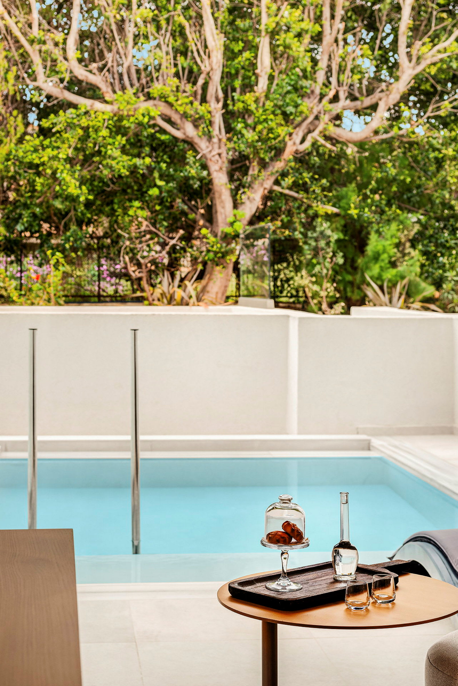 En privat pool på en terrass med ett litet bord som har drycker och snacks. (AI-genererad text)