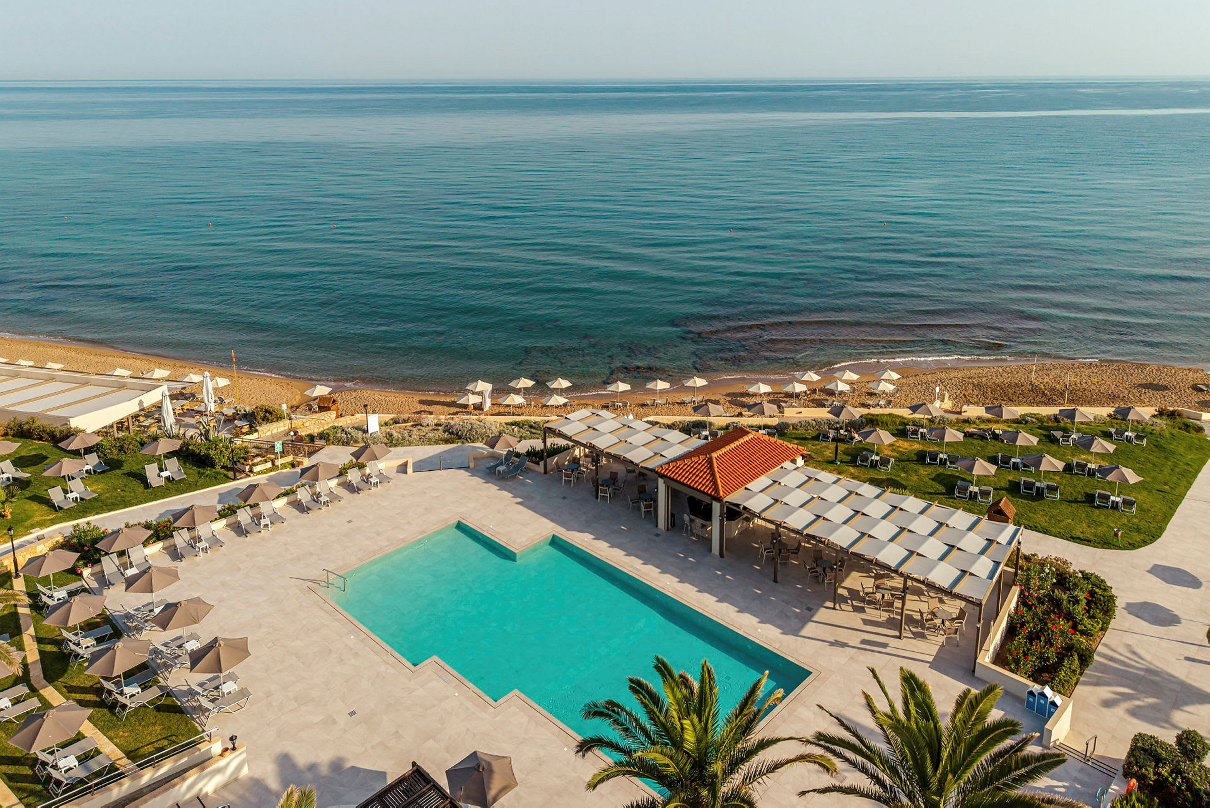 Bild av en semesteranläggning vid havet med pool, solstolar och parasoller. (AI-genererad text)