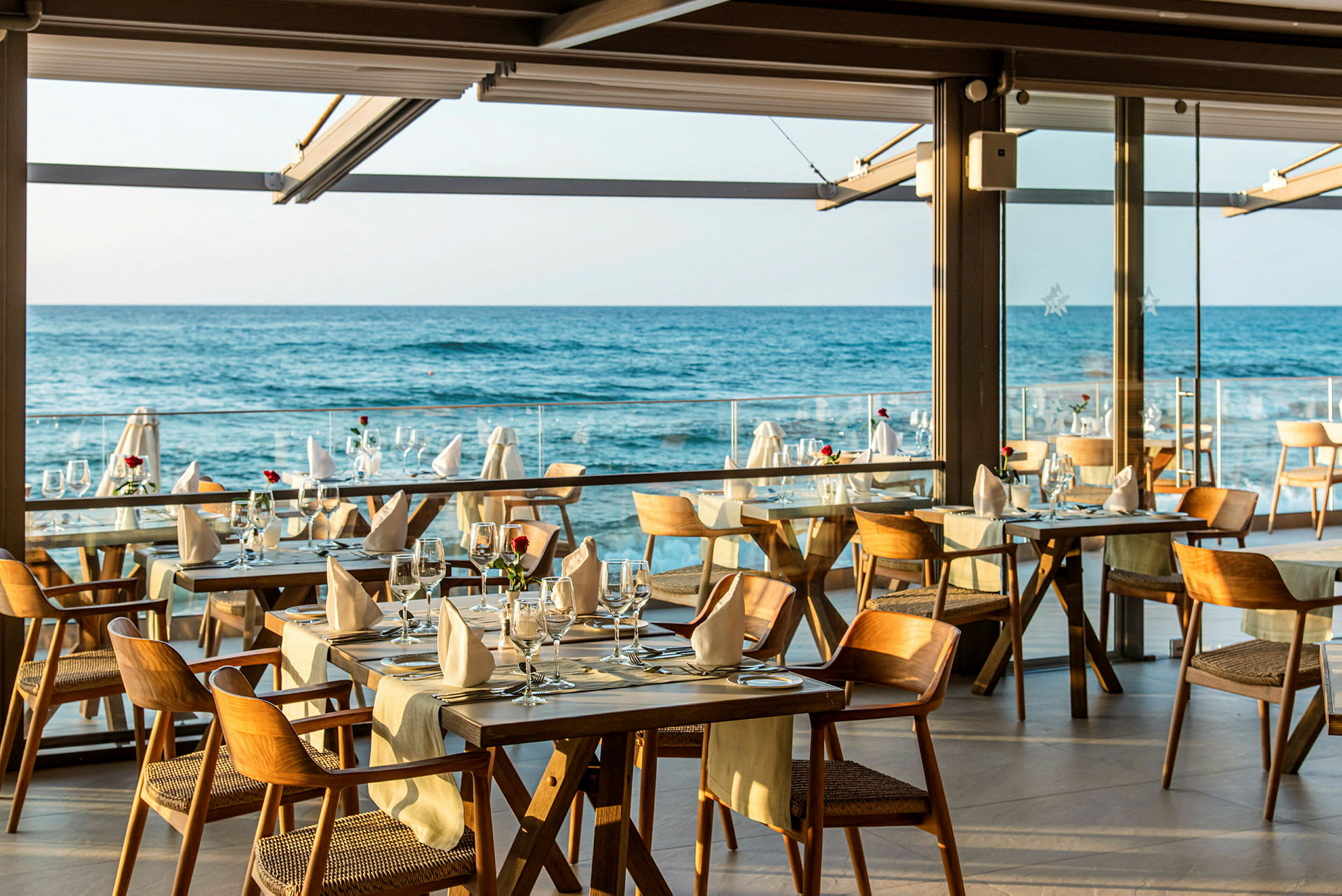 Bild på en restaurang med dukade bord och utsikt över havet. (AI-genererad text)