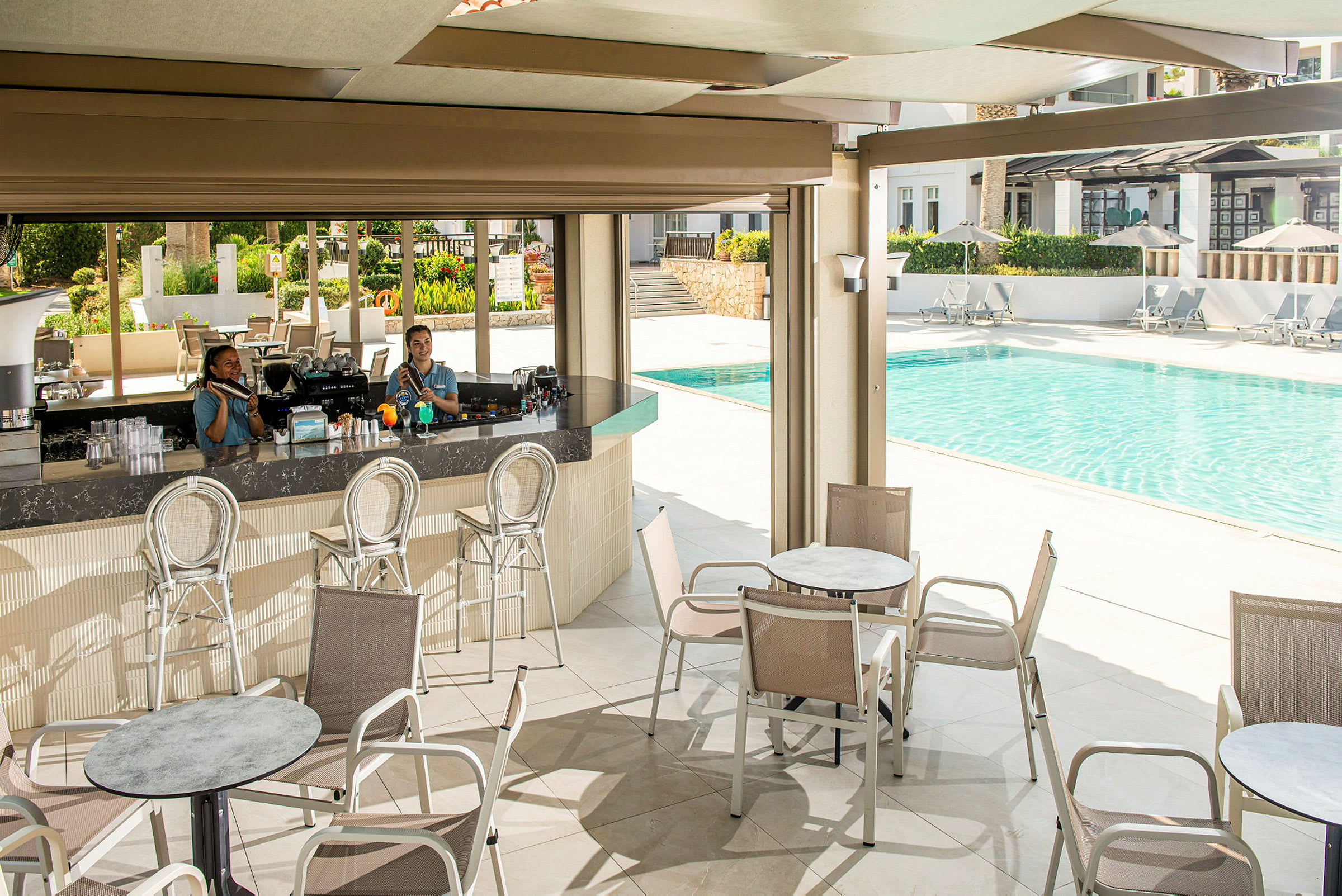 En poolbar med stolar och bord framför samt en pool i bakgrunden. (AI-genererad text)