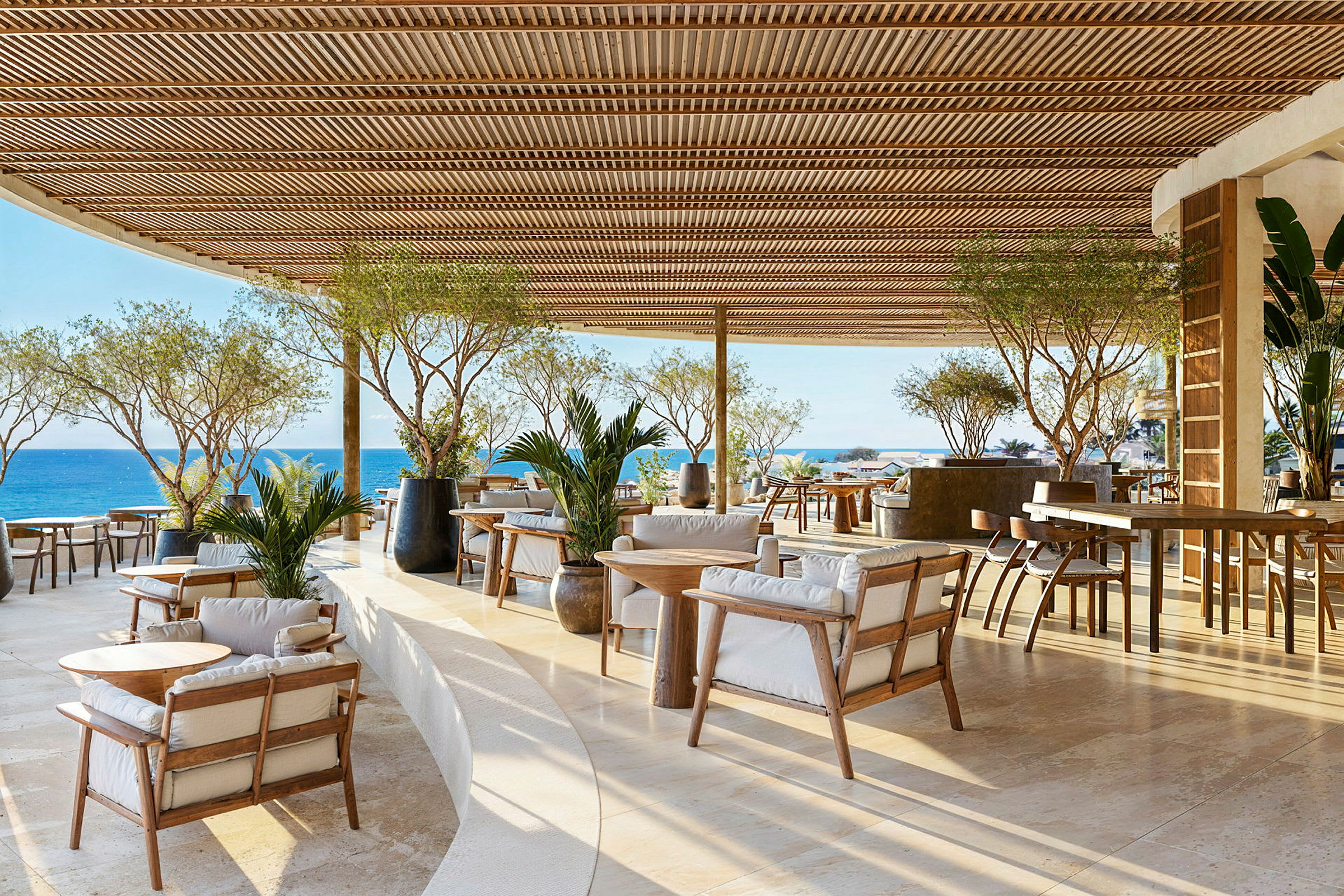 En utomhusrestaurang med träinredning och utsikt över havet. (AI-genererad text)
