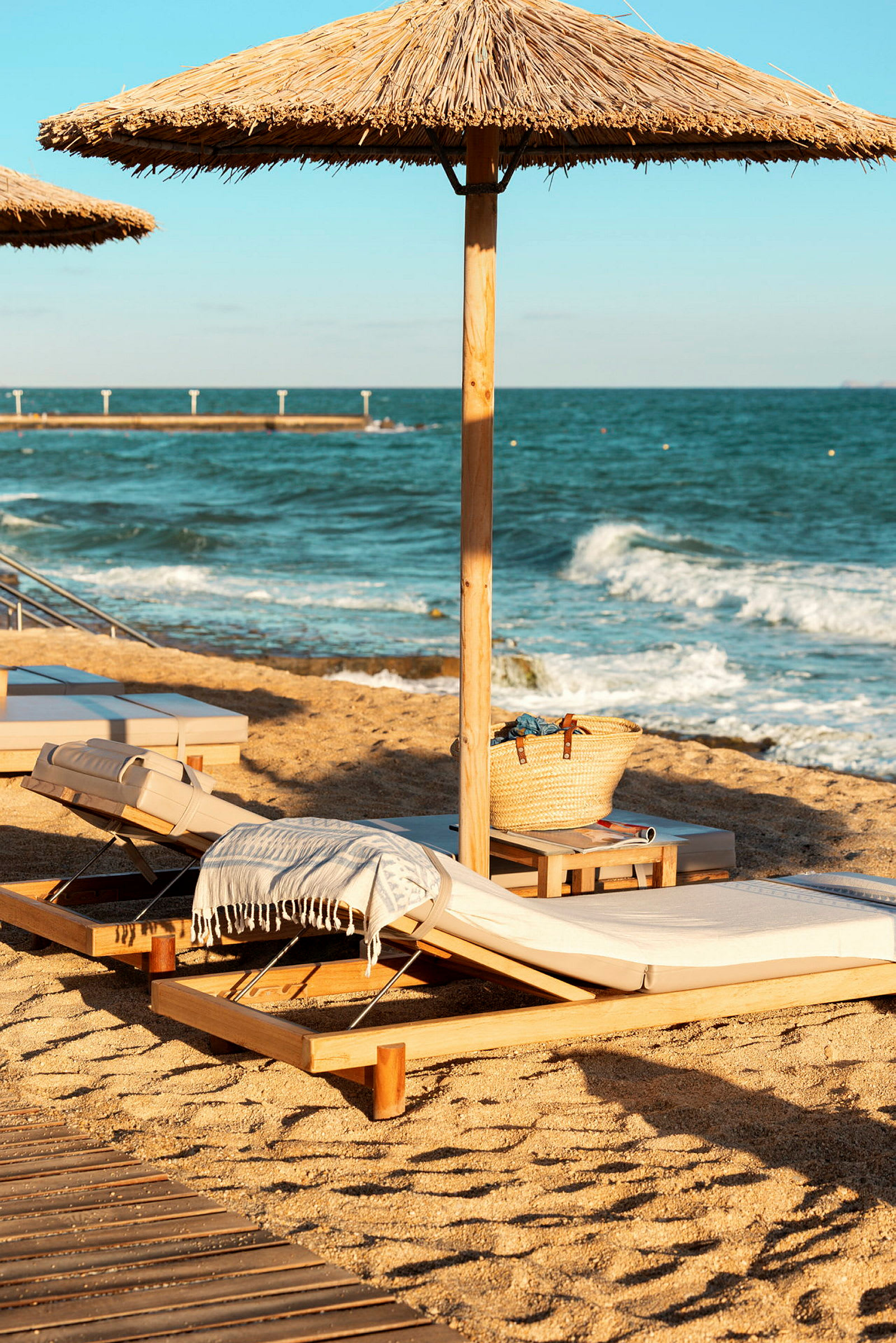 Bild av en strand med solstolar och parasoller, samt havet i bakgrunden. (AI-genererad text)