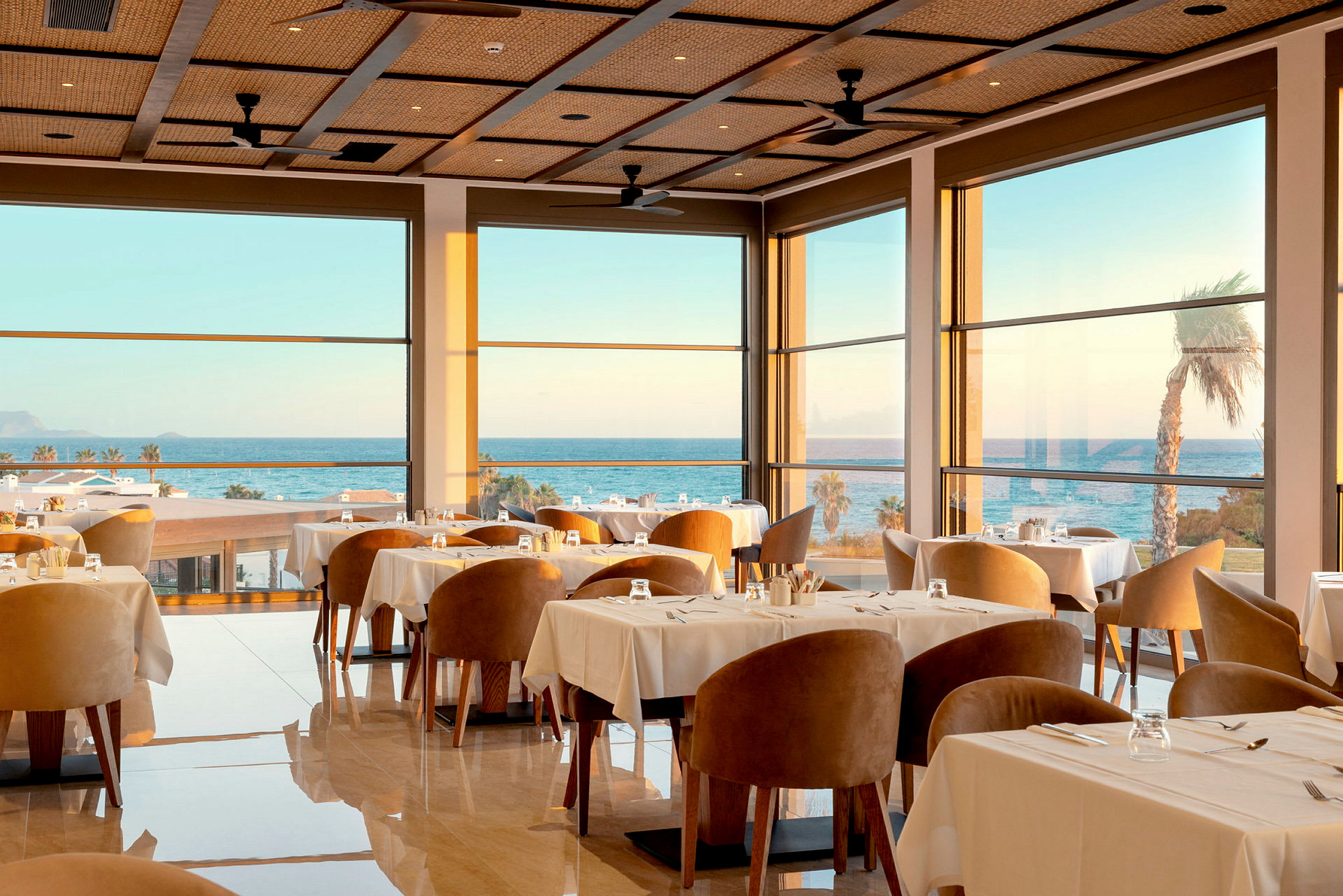 En elegant restaurang inomhus med stora fönster och havsutsikt. (AI-genererad text)