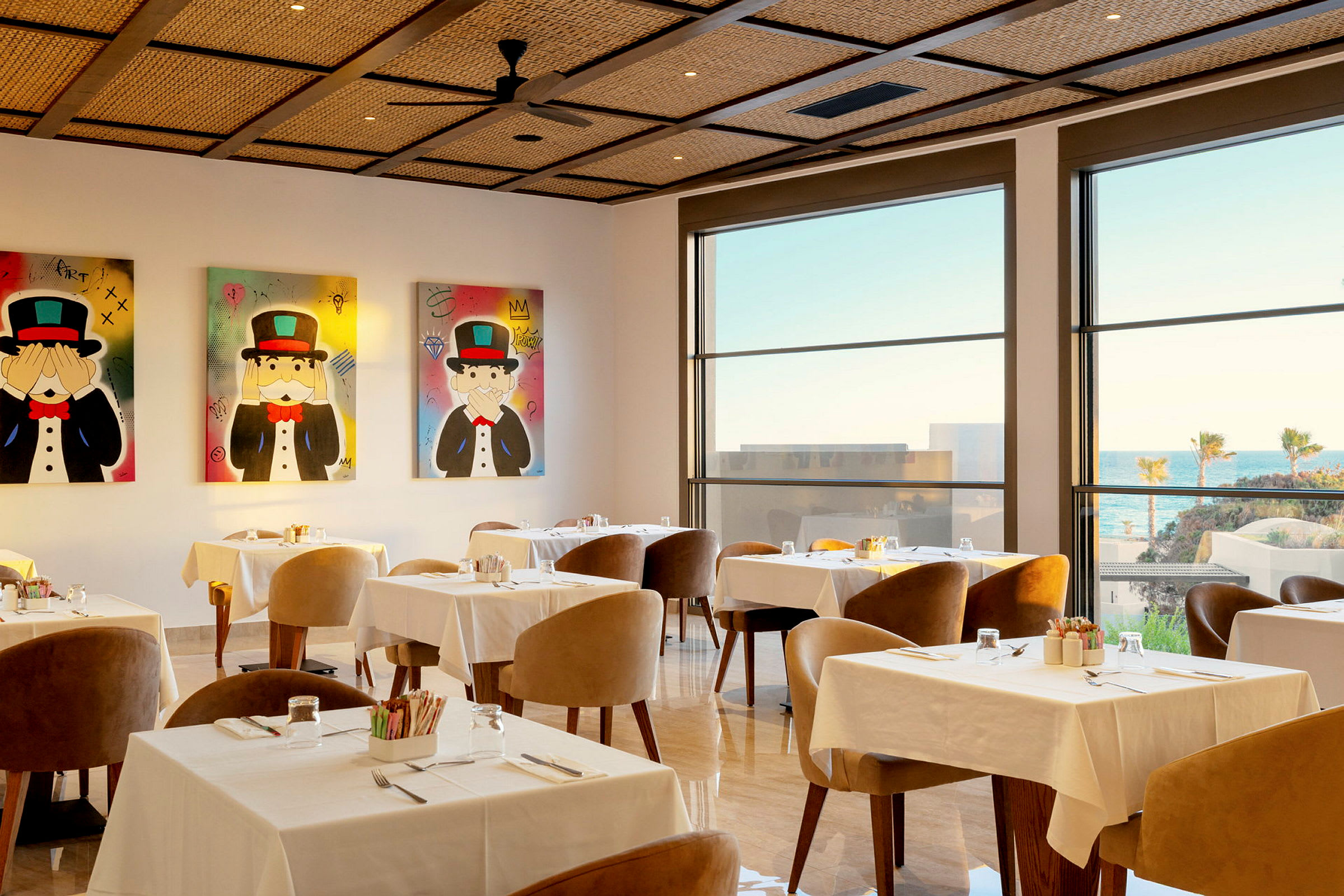 En rymlig restaurang med stora fönster som släpper in naturligt ljus, dekorationer på väggarna och dukade bord. (AI-genererad text)