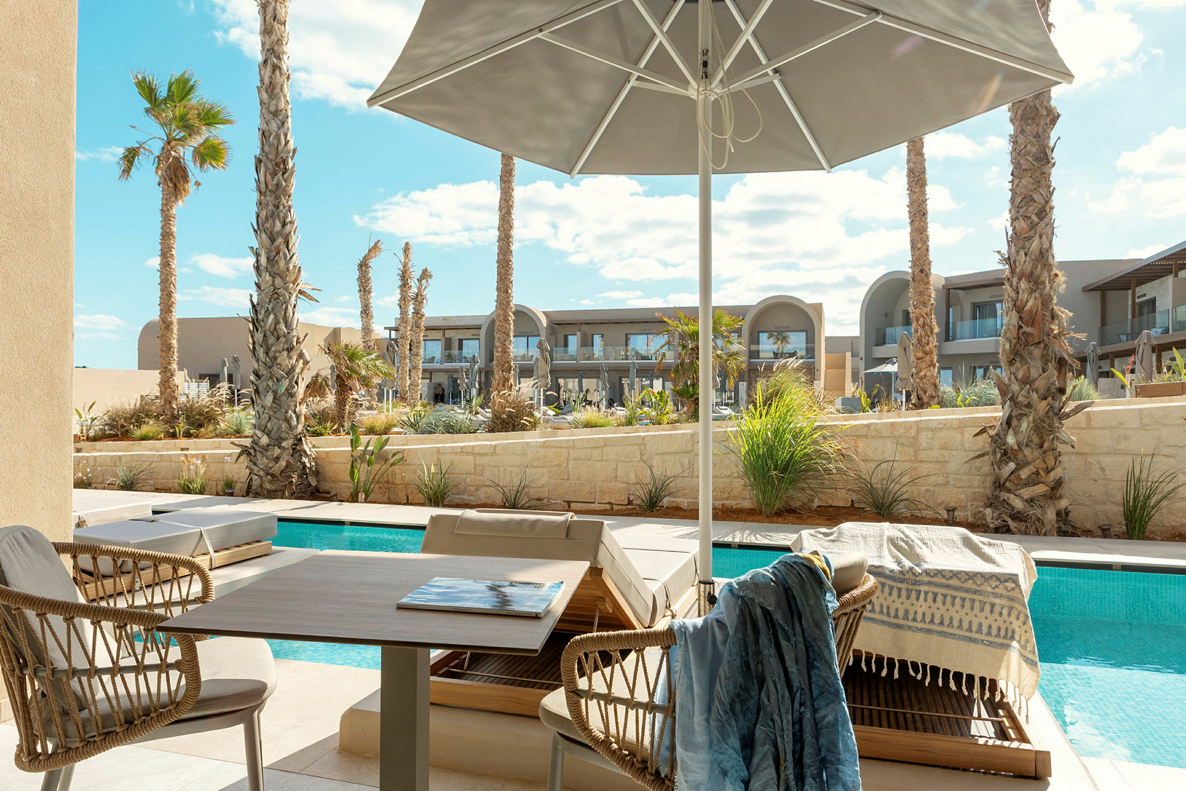 Solterrass med utsikt över pool och palmer, med utemöbler under parasoll. (AI-genererad text)