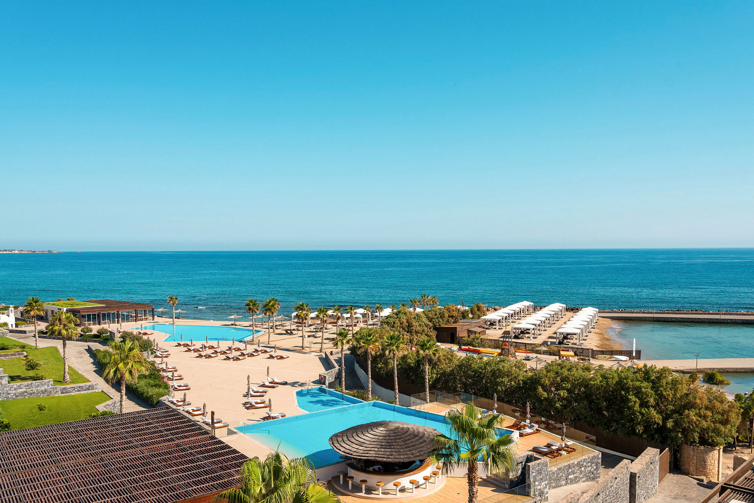 Utsikt över en resort med pool, solsängar, palmer och hav i bakgrunden. (AI-genererad text)