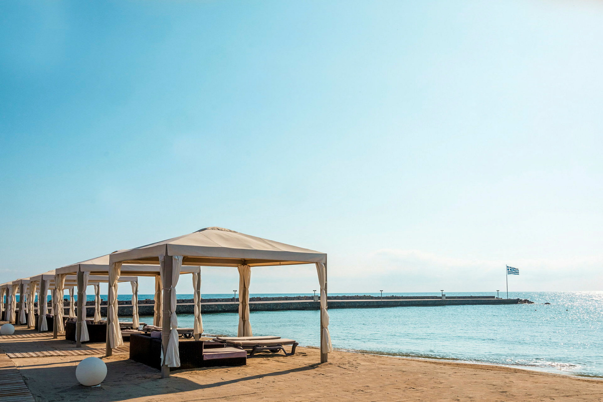 Strand med paviljonger och sittplatser, havet i bakgrunden. (AI-genererad text)