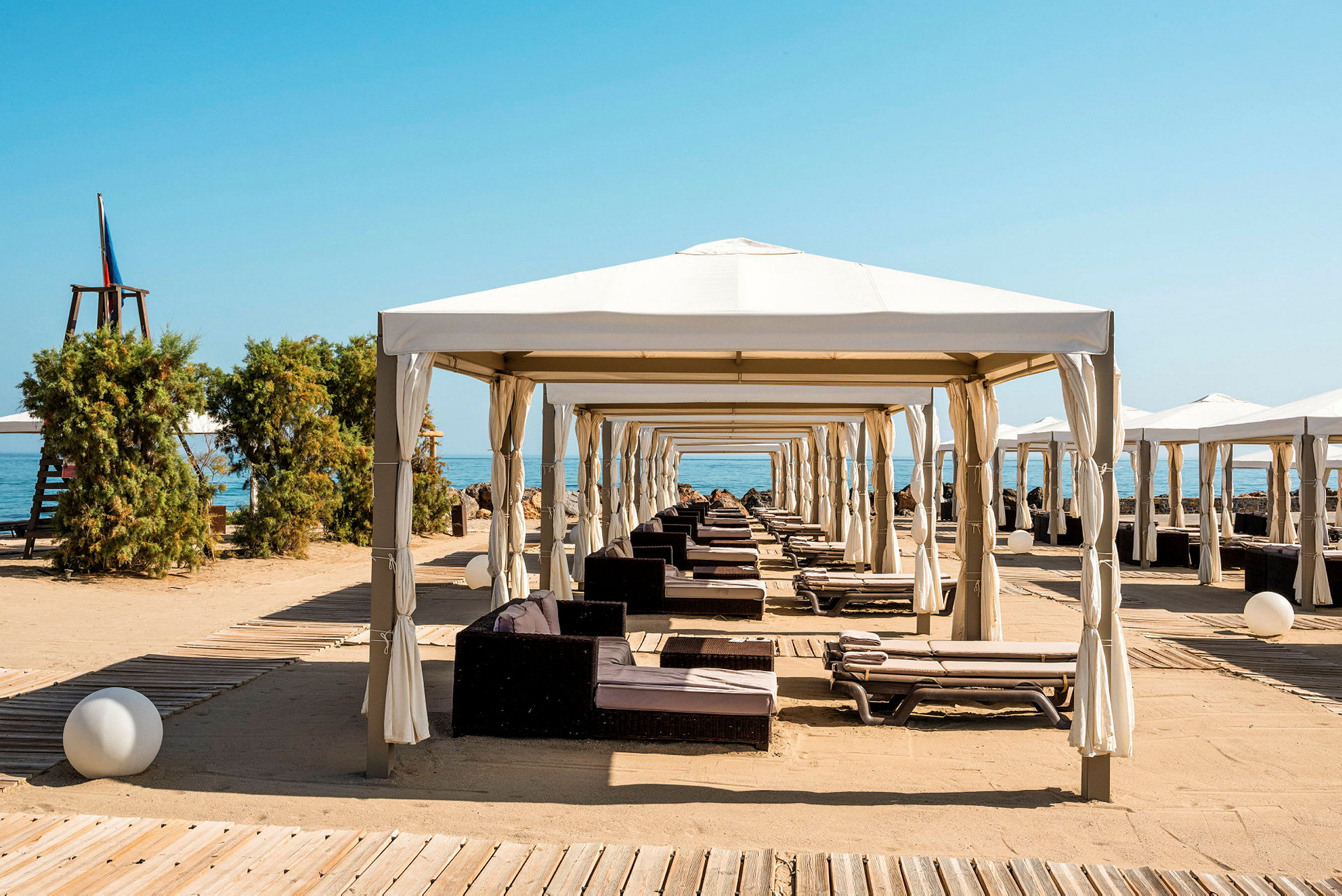Strandpaviljonger med solbäddar och sand. (AI-genererad text)